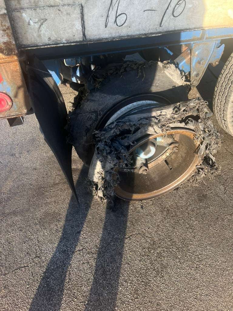 Damaged wheel with burned and melted tire on a truck, showing significant fire damage.