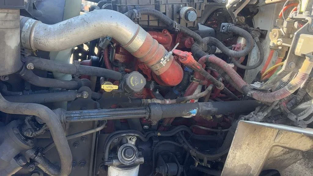View of a diesel engine with various pipes, hoses, and engine components visible, showing some dirt and grime.