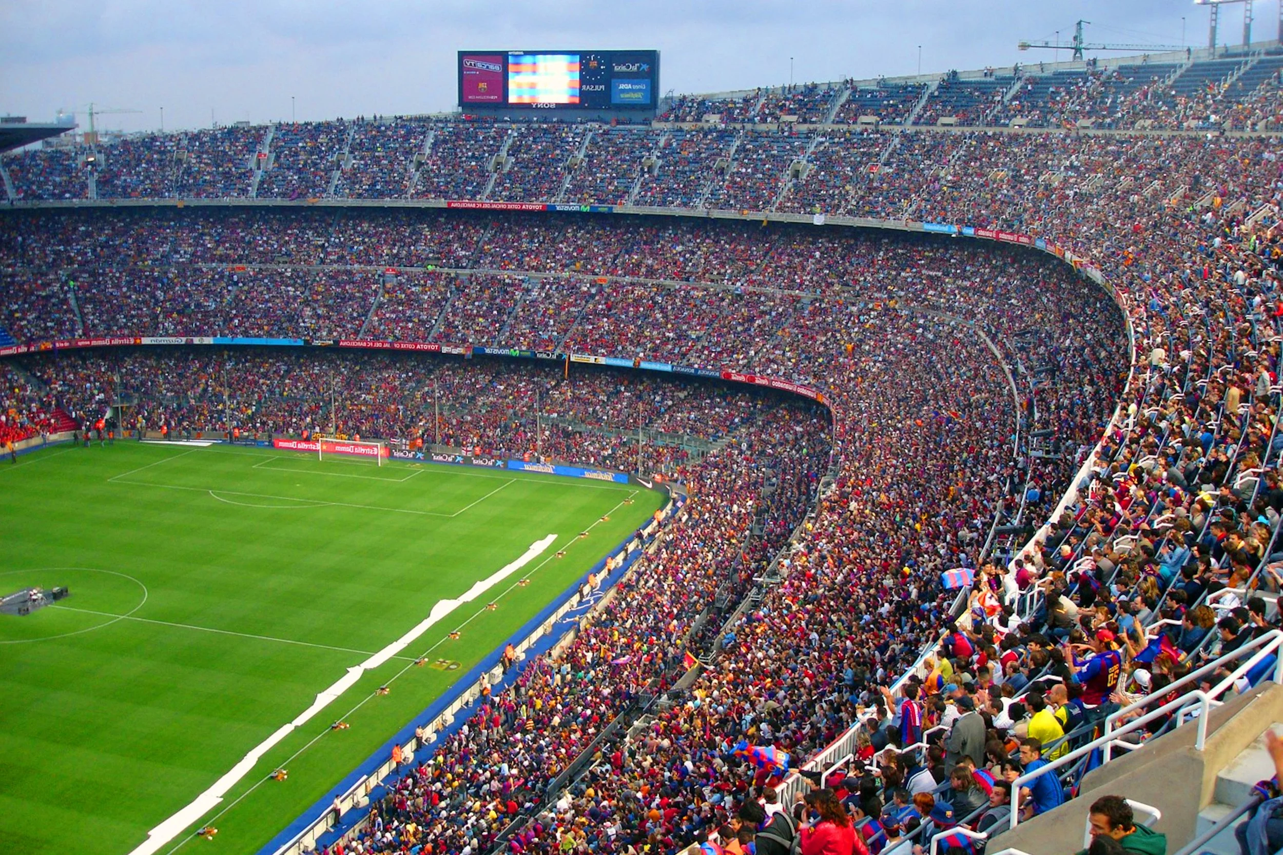 Crowd of spectators filling the stands of a large football stadium during a game.