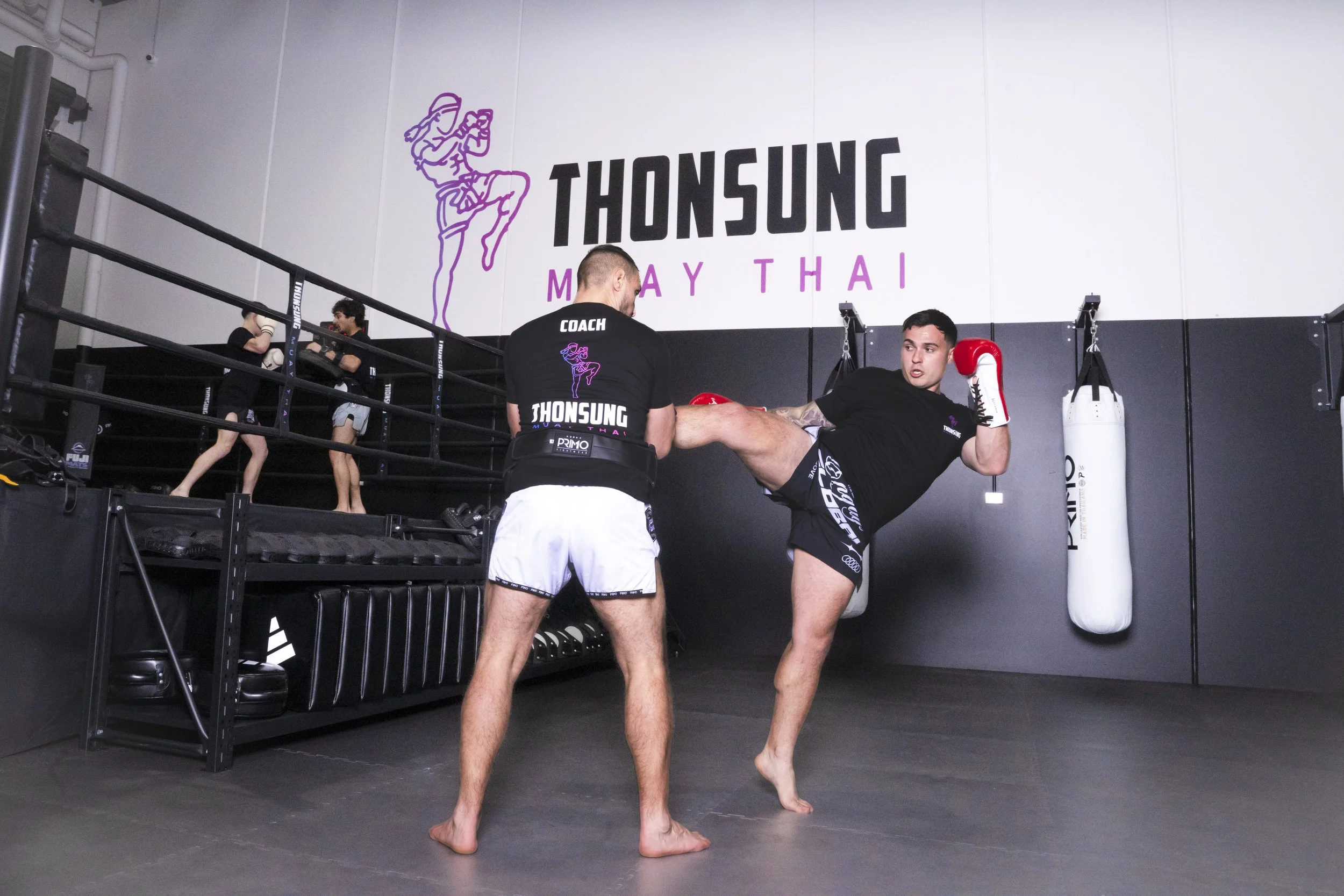 Thonsung Muay Thai Adult student executing a roundhouse kick on the pads, Epping Victoria.