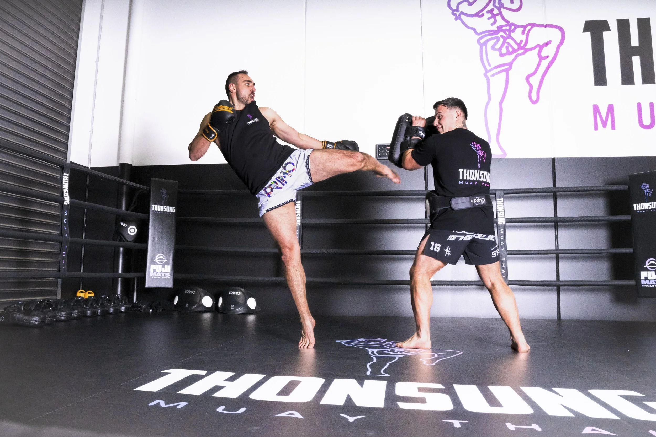 Thonsung Muay Thai, Coach Tome Kokarevski executing a high head kick on the pads in a full size Muay Thai Ring, Epping Victoria.