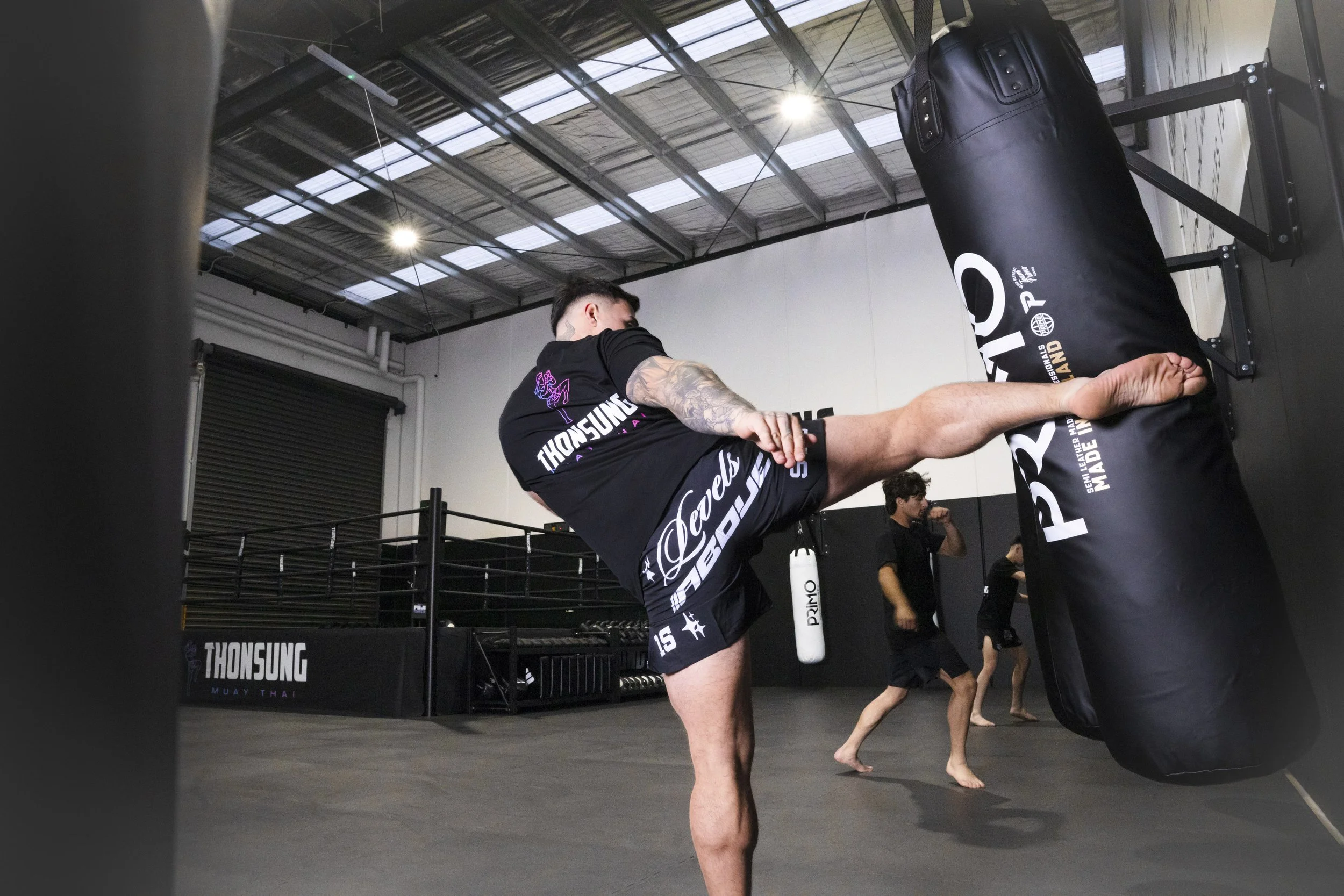 Thonsung Muay Thai Adult student practicing a heavy bag roundhouse kick, Epping Victoria.