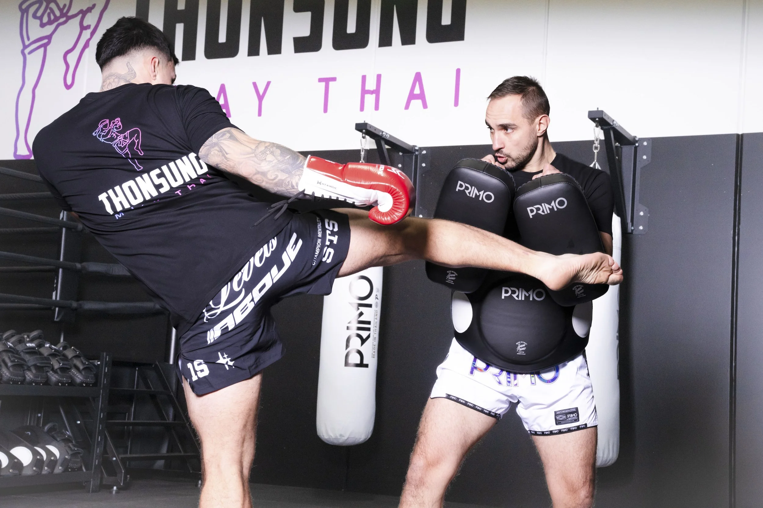 Thonsung Muay Thai Adult student executing a roundhouse kick on the pads, Epping Victoria.