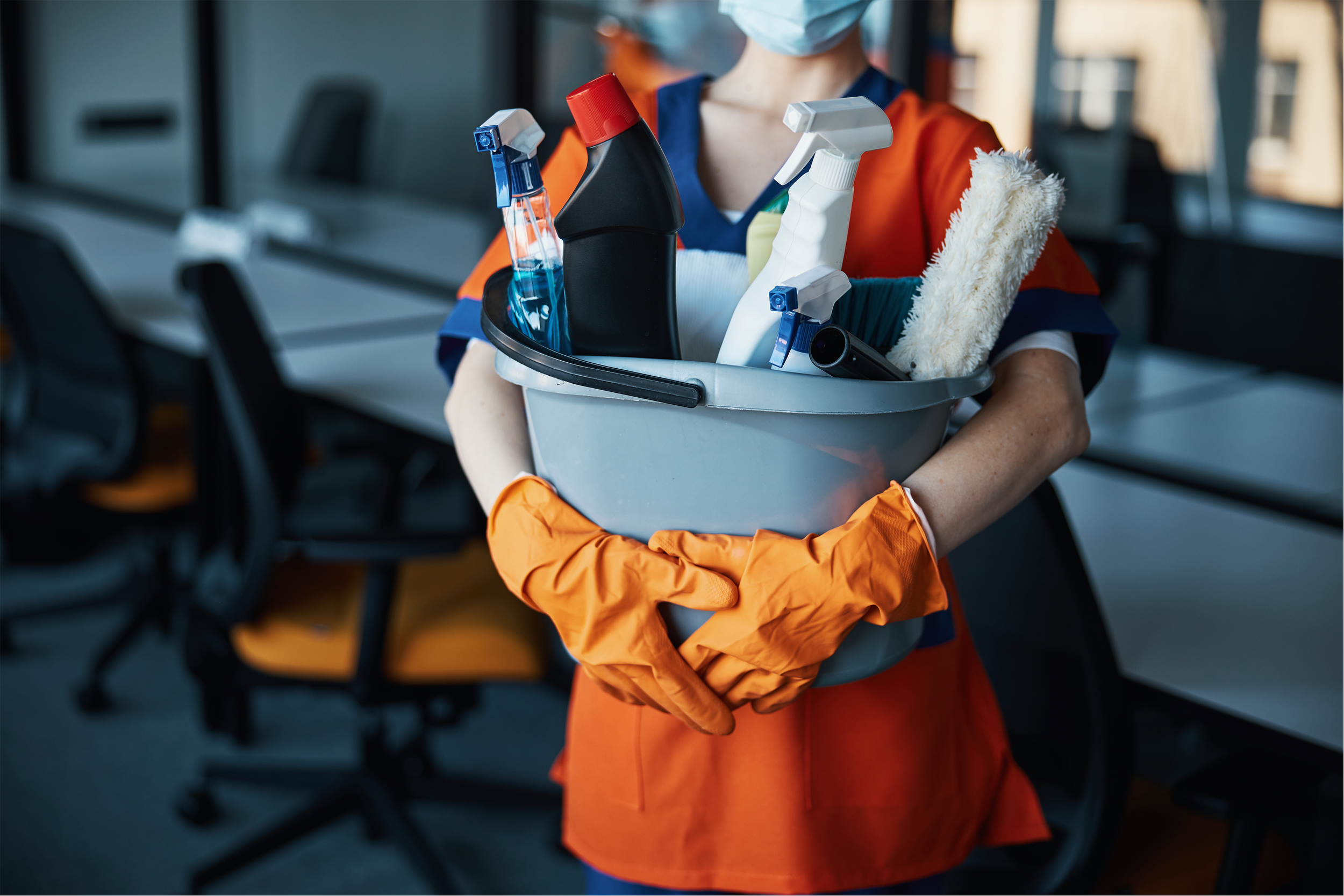 Janitorial professional carrying commercial cleaning supplies for facility maintenance.