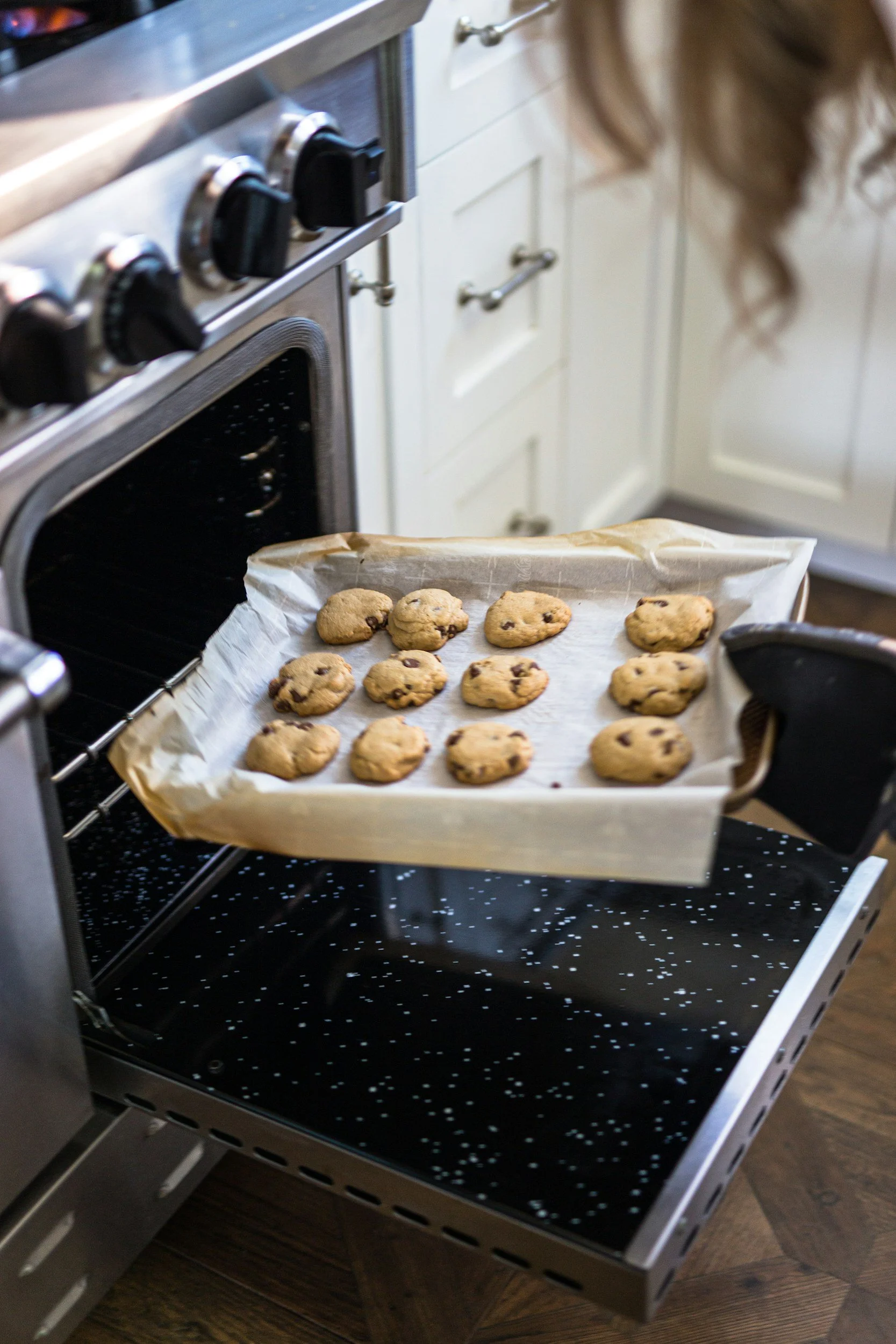 Chocolate chip cookies cooling on a baking sheet in an oven in a home kitchen.