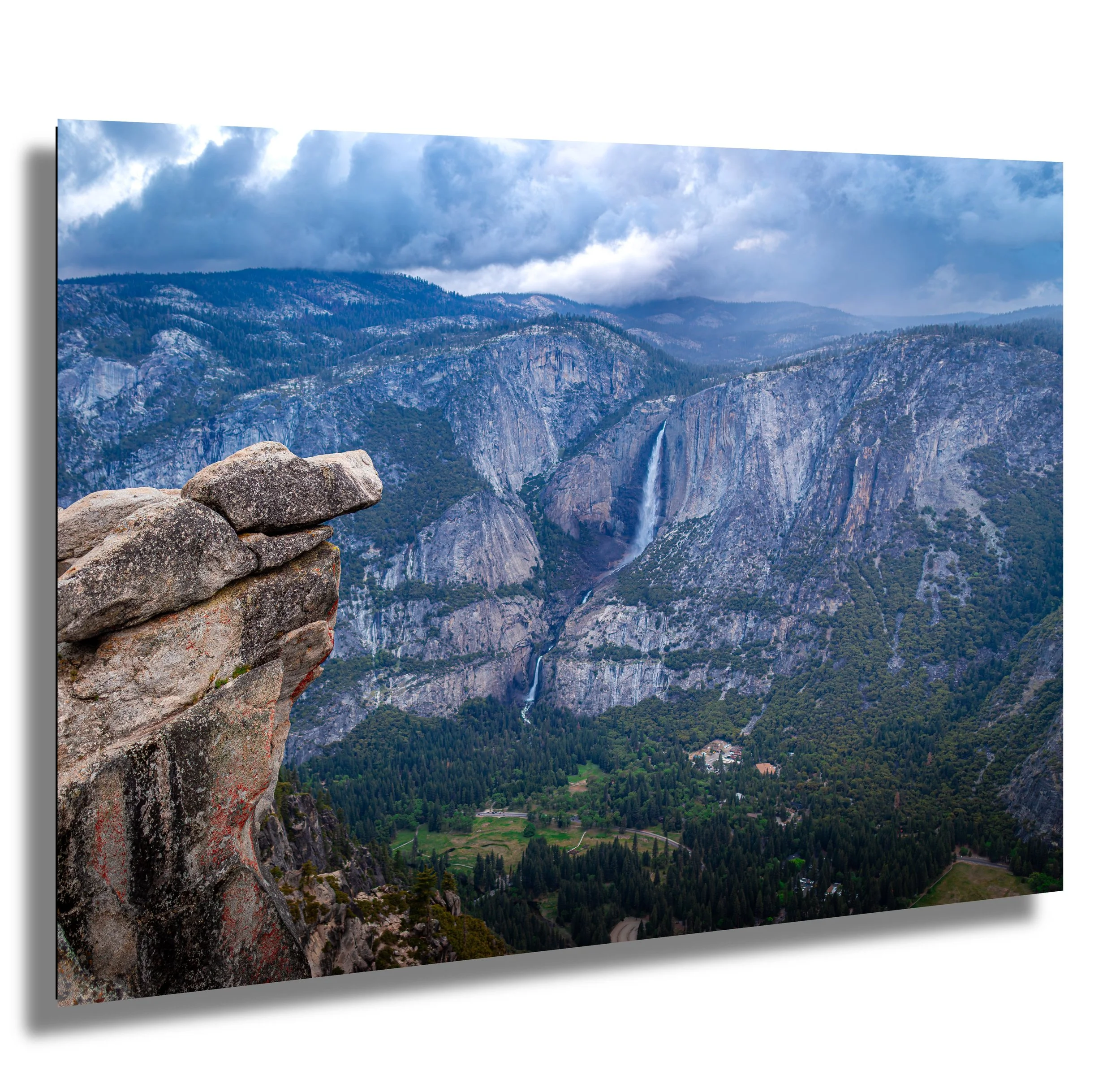 Scenic view of Yosemite Valley with waterfalls, granite cliffs, forested areas, and cloudy sky