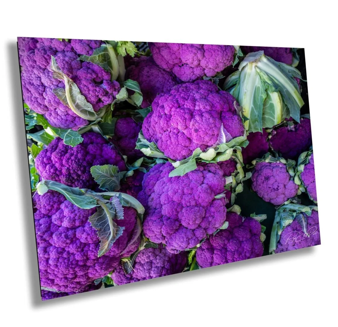 Close-up of multiple purple cauliflower heads with green leaves.