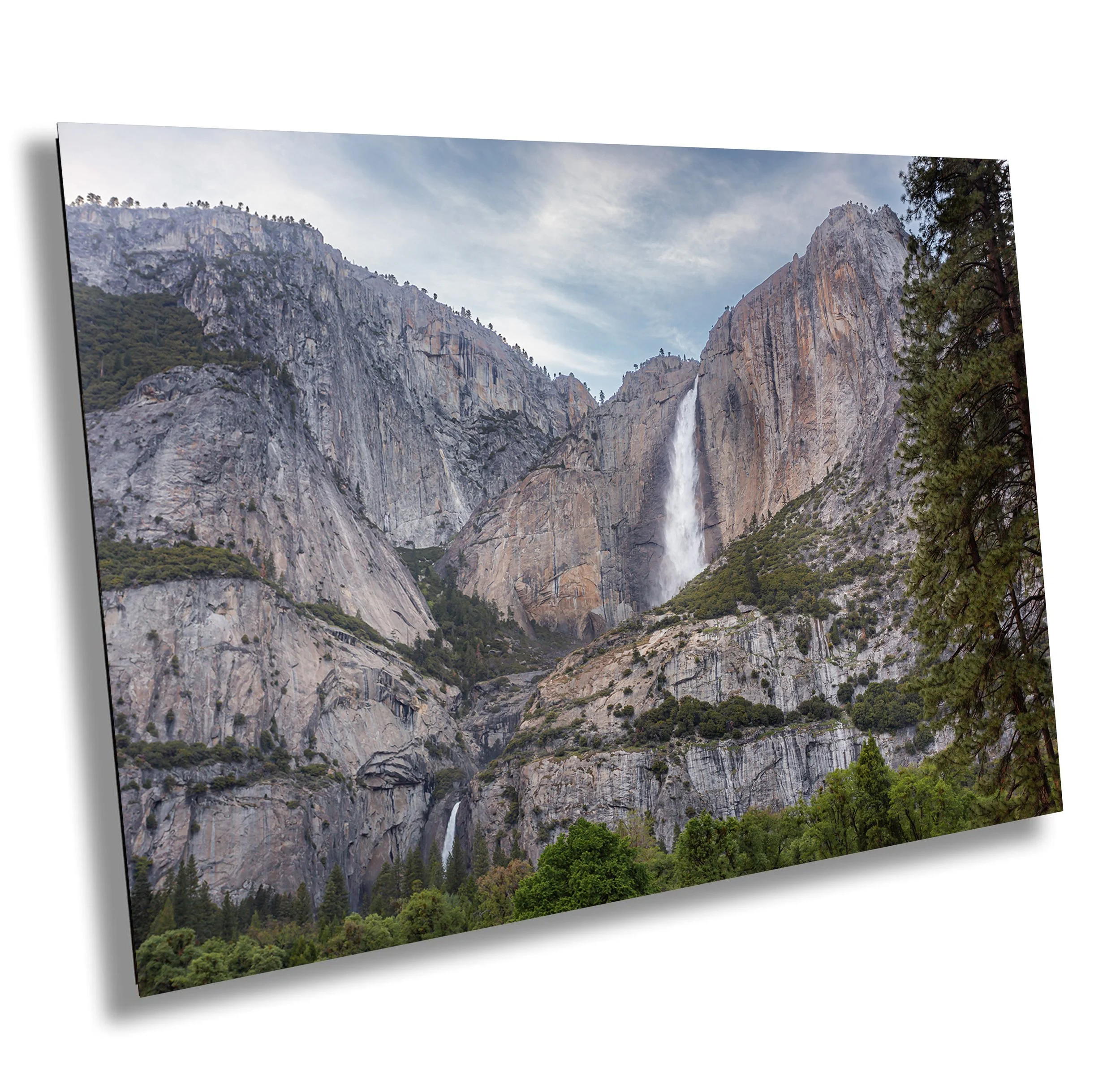 A scenic mountain landscape with waterfalls cascading down rocky cliffs and trees in the foreground.