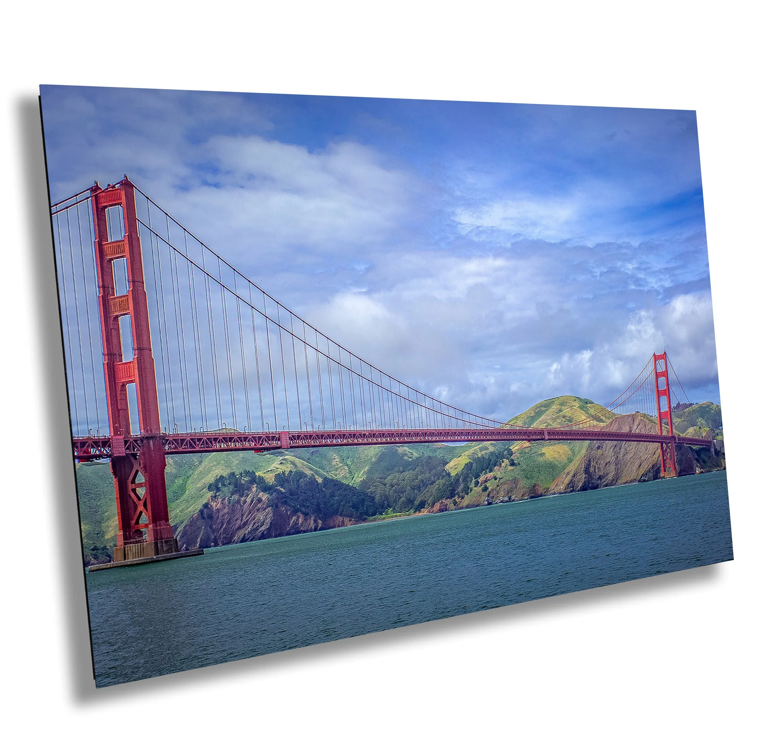 Photo of the Golden Gate Bridge in San Francisco, California, with a partly cloudy sky and green hills in the background.