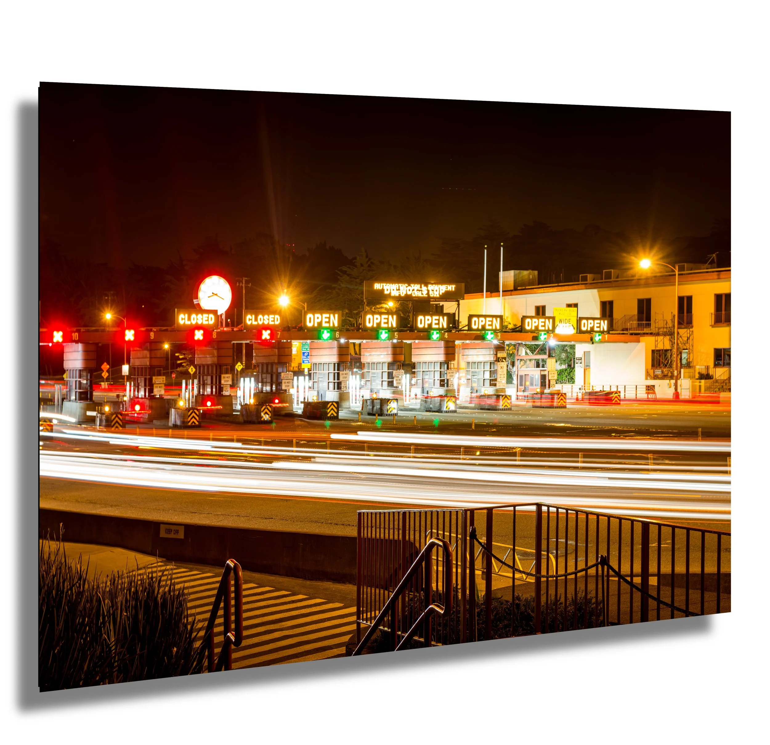 Nighttime toll booth with open and closed signs, light trails from passing vehicles, and streetlights illuminating the scene.