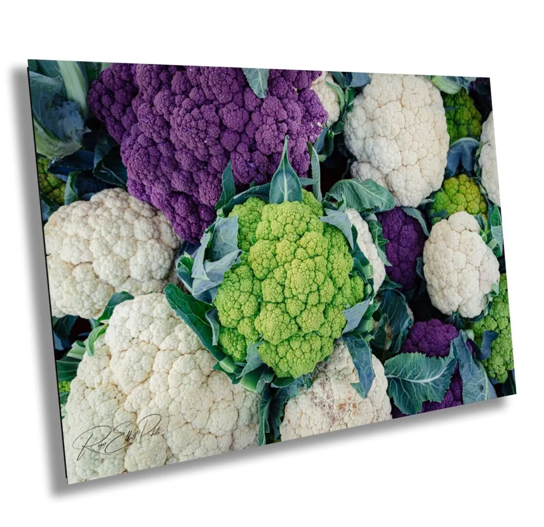 A colorful display of cauliflower and broccoli heads with green leaves