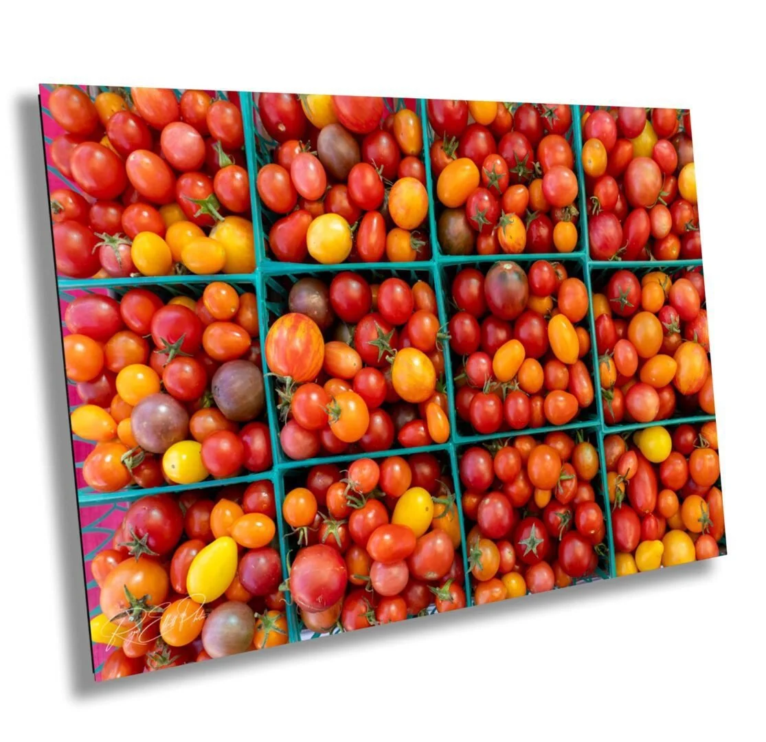 A display of various ripe cherry and grape tomatoes sorted in green plastic baskets.