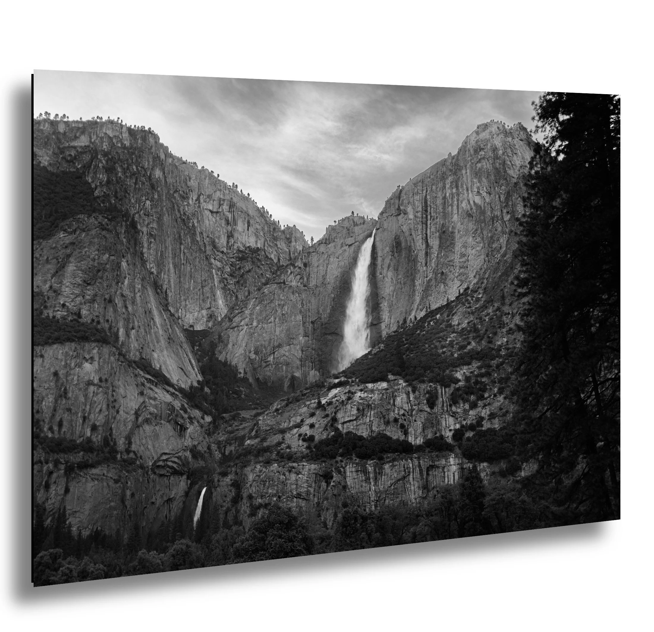 Black and white photograph of a mountain landscape with a waterfall cascading down from the cliffs.