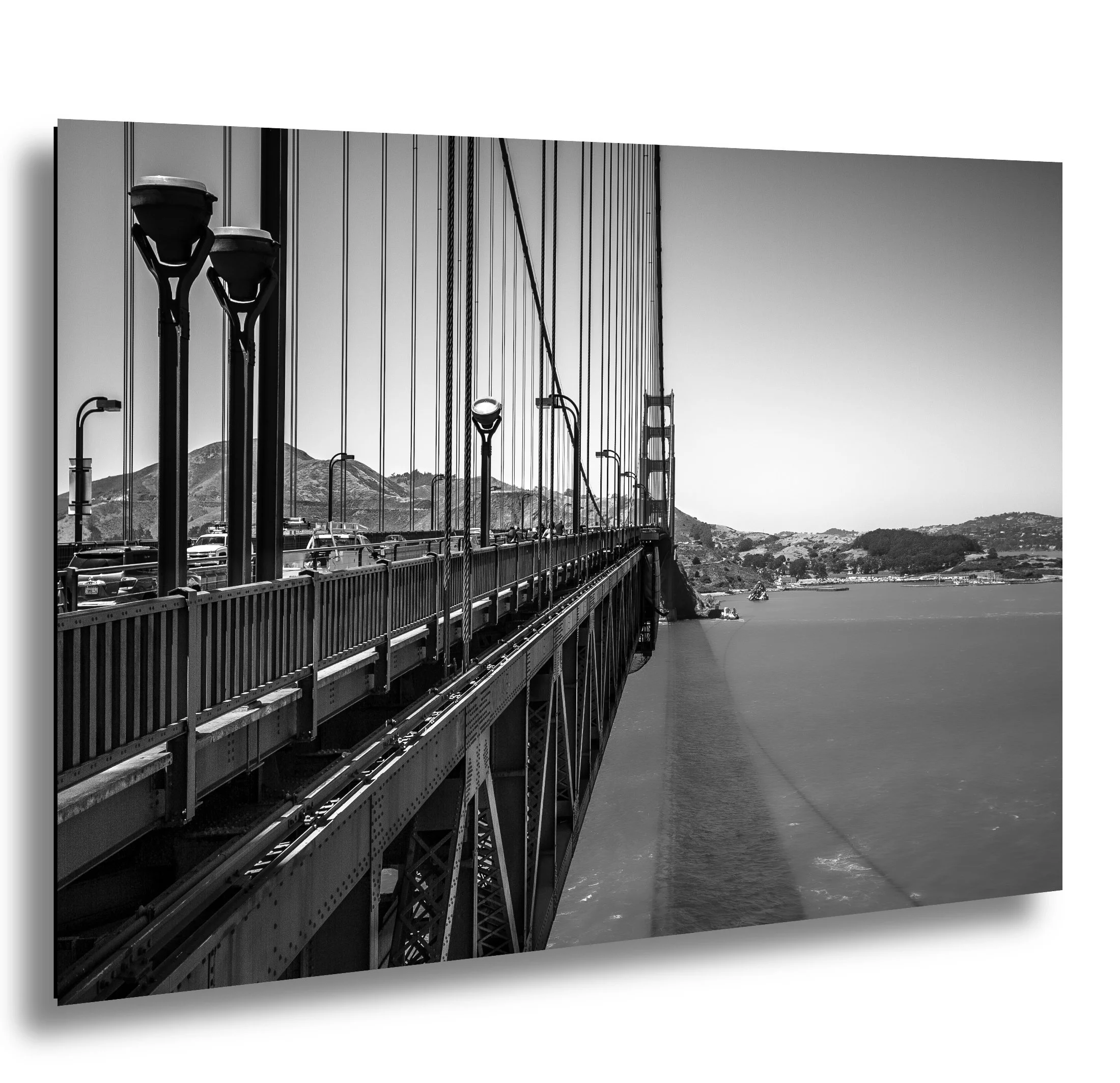 Black and white photo of the Golden Gate Bridge in San Francisco with cars on the roadway and the city and hills in the background.