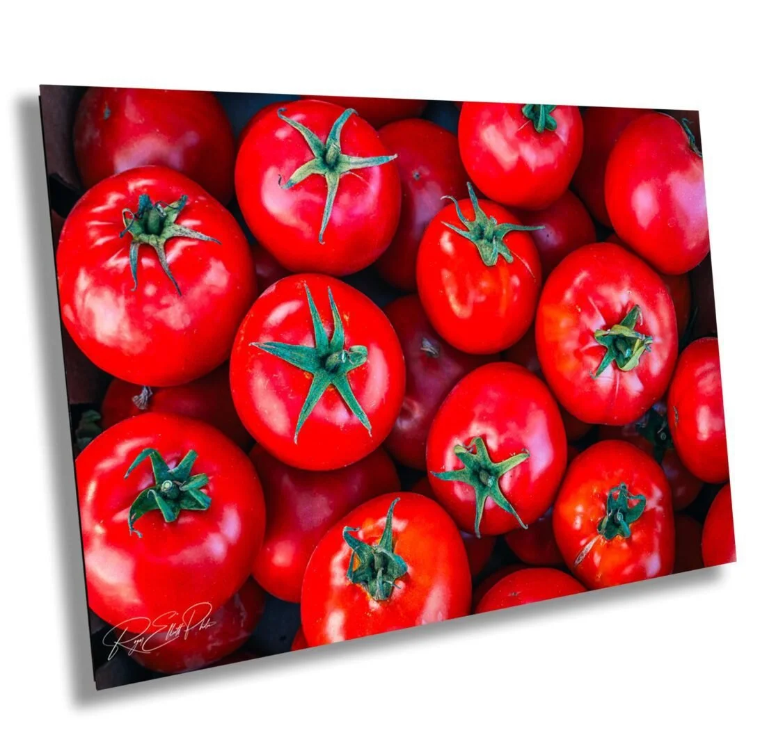 A close-up of fresh, ripe red tomatoes with green stems, arranged in a pile.