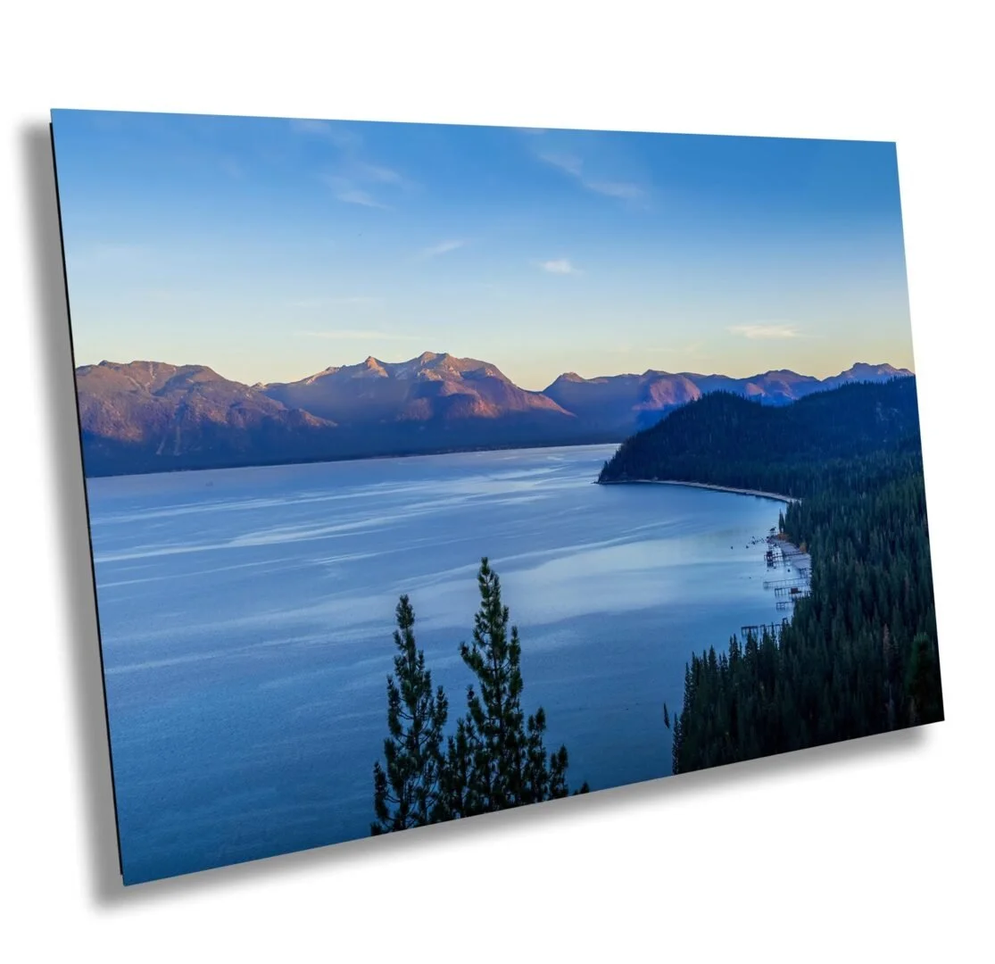 Scenic view of a large lake surrounded by forested hills and mountains under a clear blue sky.