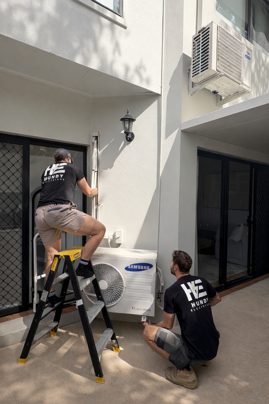 Hundy Electrical team installing split system air conditioning outdoor unit on Gold Coast home