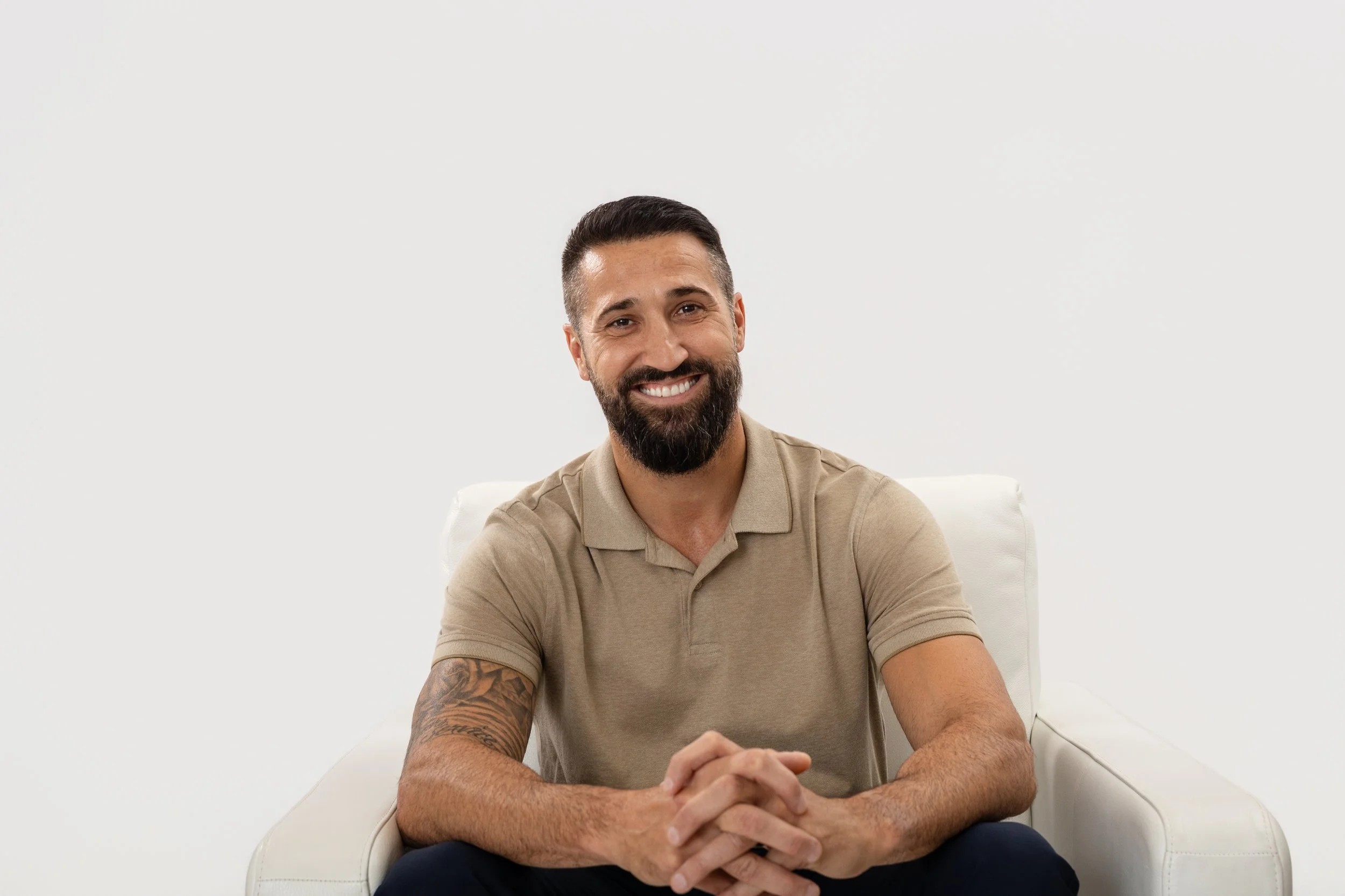 Color portrait of man with a beard and short hair, wearing a light shirt, sitting and smiling..
