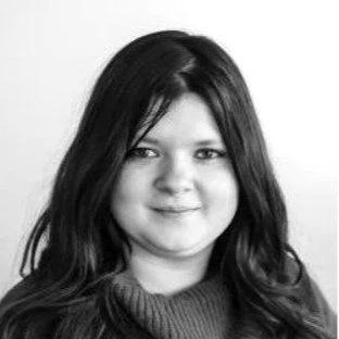 A black-and-white portrait of a young woman with long, dark hair, smiling lightly, wearing a sweater.