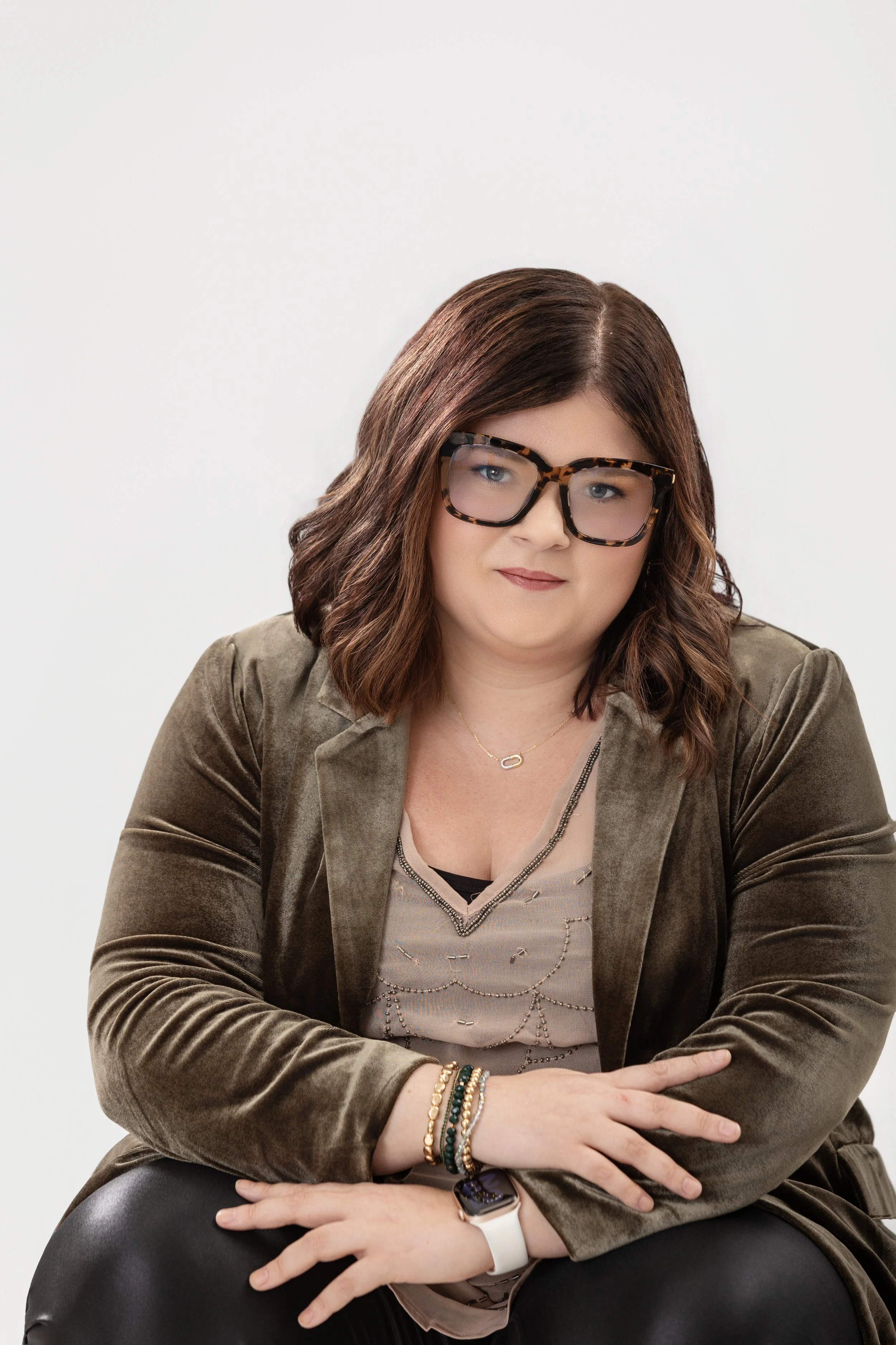 Color portrait of woman with glasses and short brown curled hair sitting and smiling