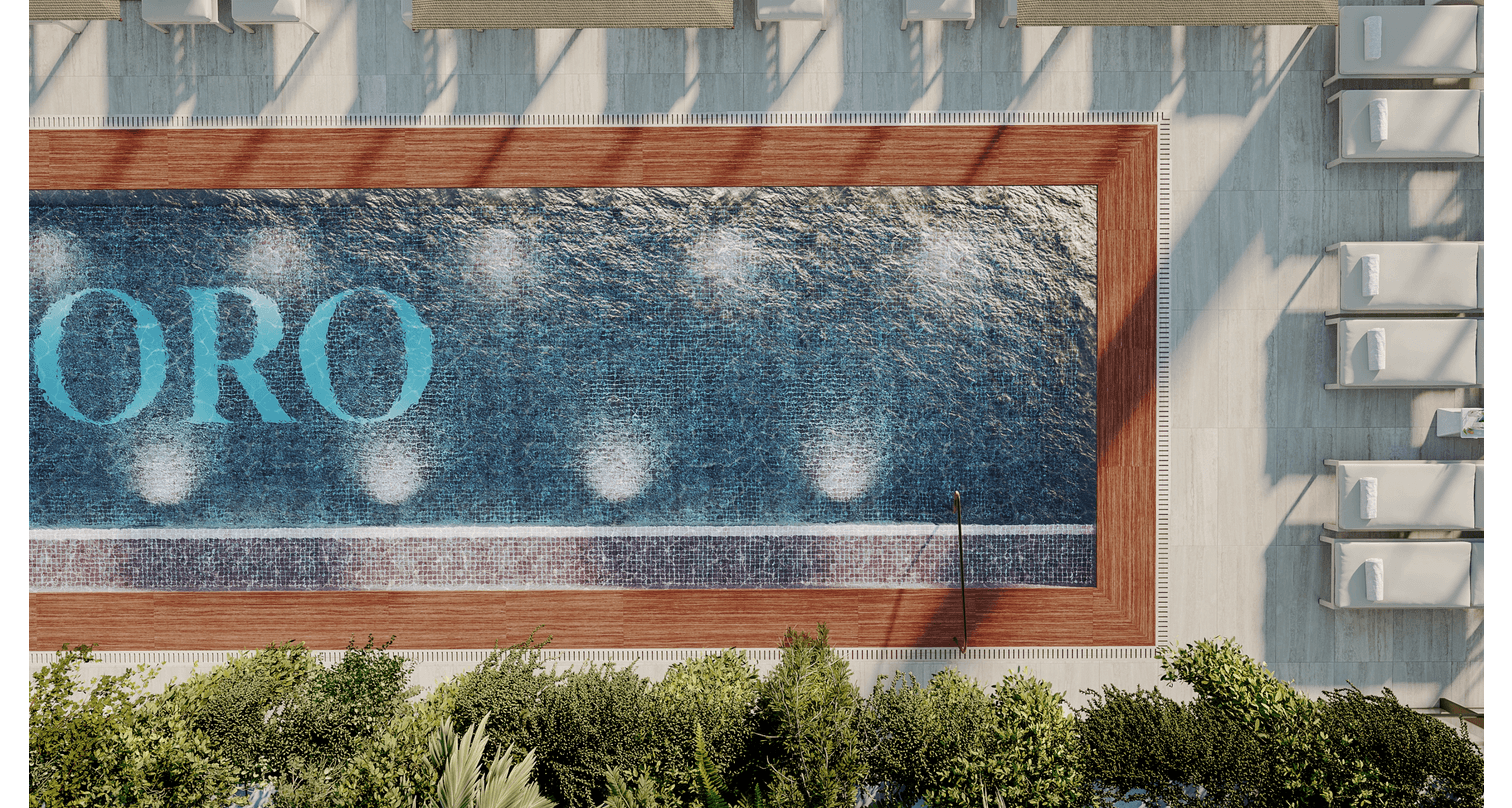 An outdoor swimming pool with water spray features, surrounded by a wooden deck and lounge chairs, with greenery at the bottom and shaded by the building's structure.