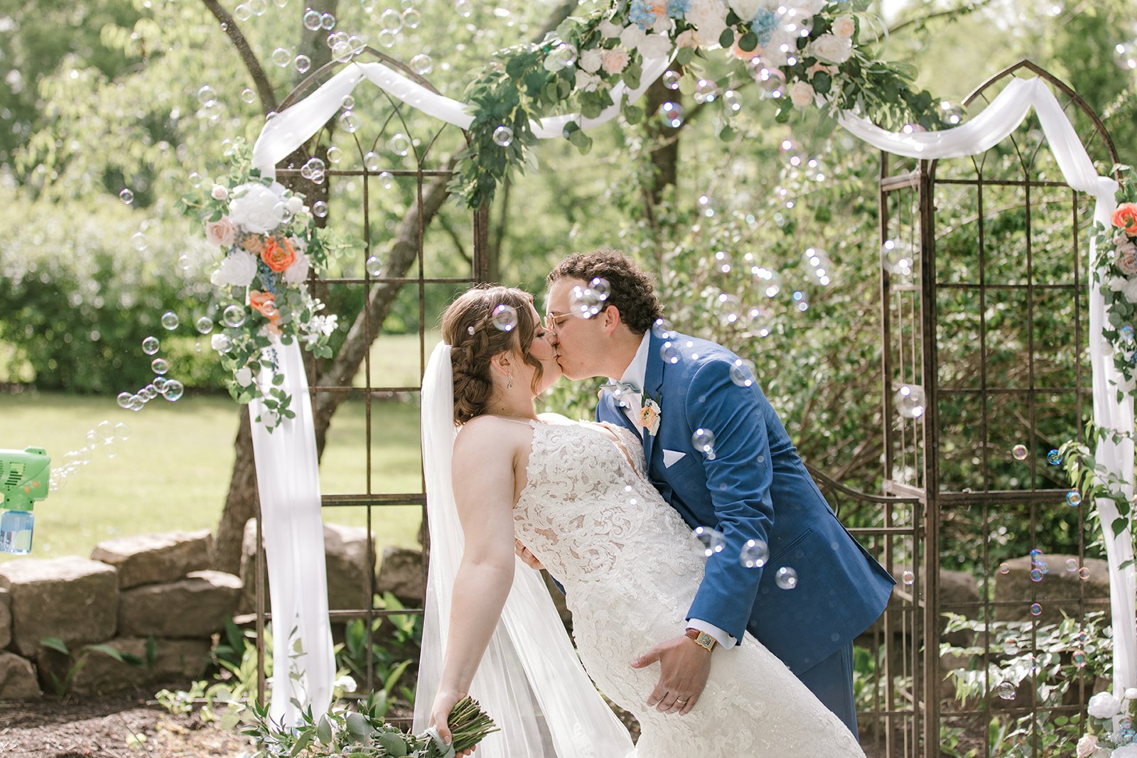 Bride and groom share a kiss during their bubble send‑off at The Gish Barn wedding in Rittman, Ohio, planned by MTM Weddings & Events.
