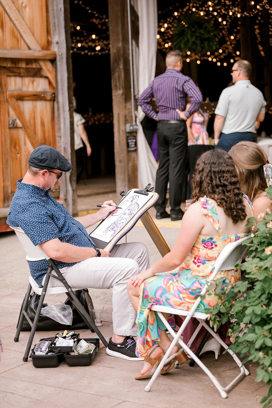 Caricature artist from Capture This! Entertainment sketching wedding guests at The Gish Barn in Rittman, Ohio planned by MTM Weddings & Events.