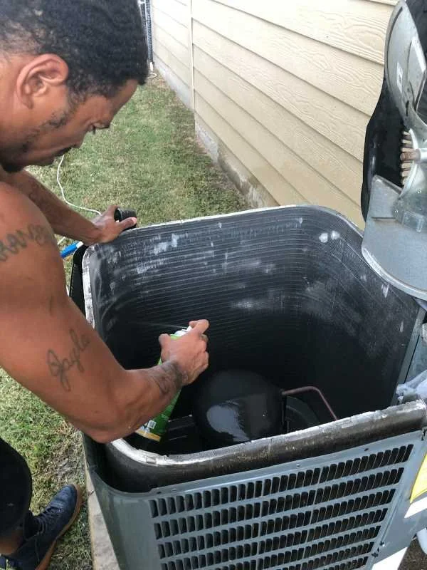 A Radical Air Technician cleaning the  outdoor air conditioning unit.