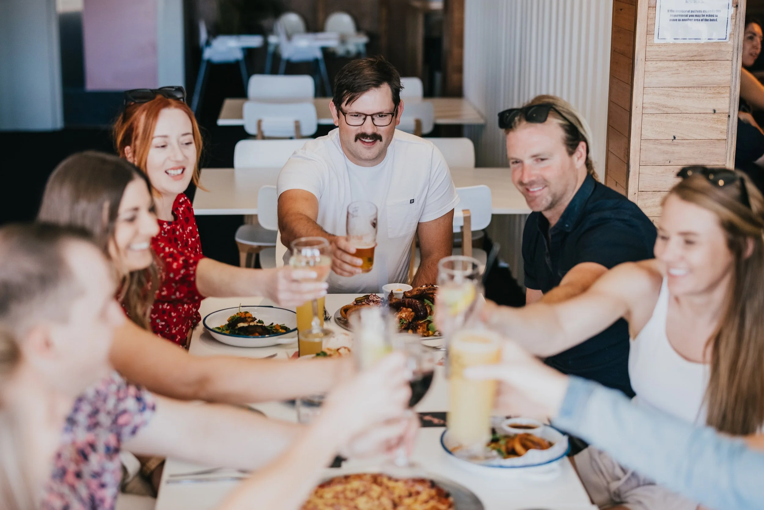 Group of people having a toast at a restaurant table with food and drinks.