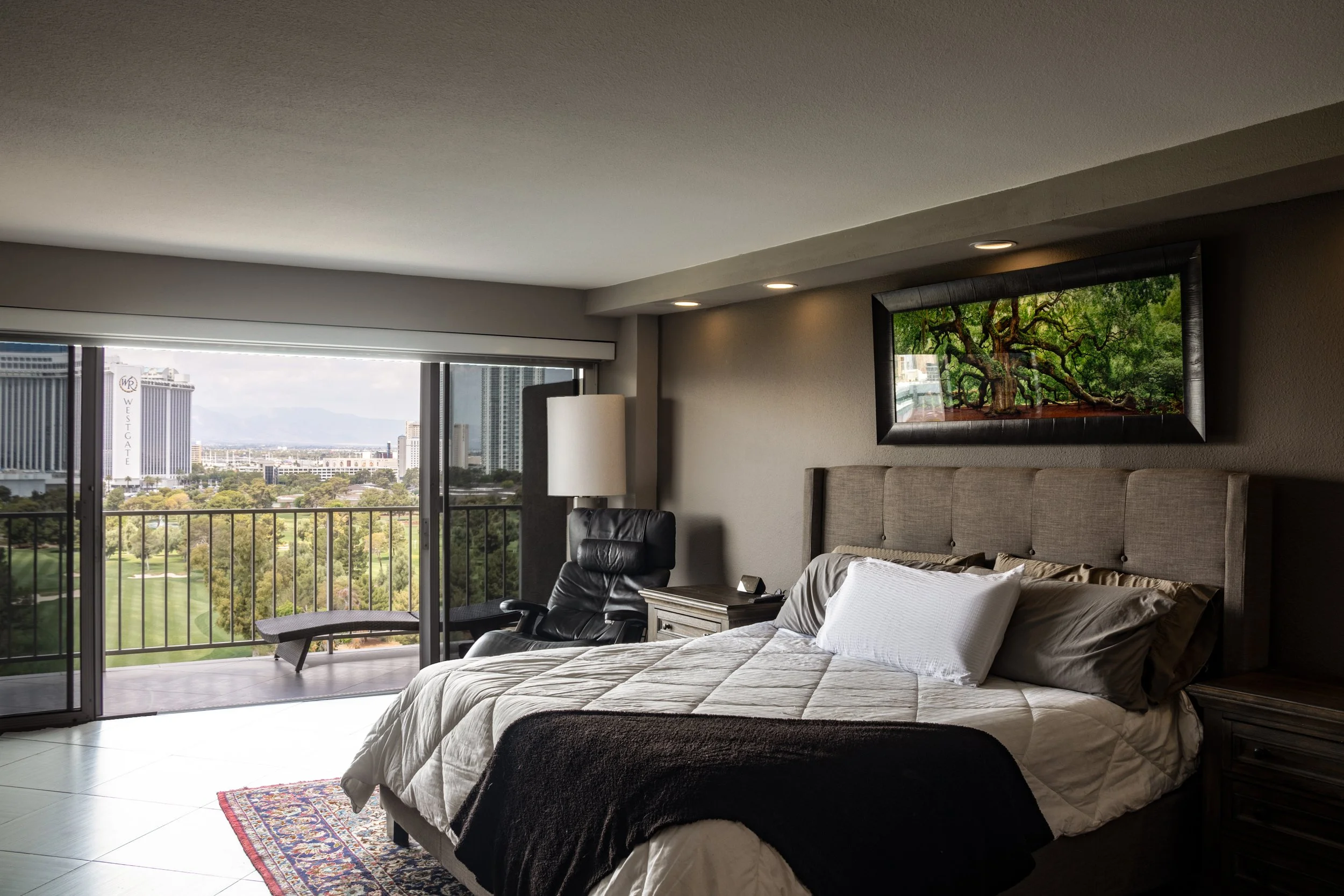 Interior of a hotel room with a bed, balcony, and city view