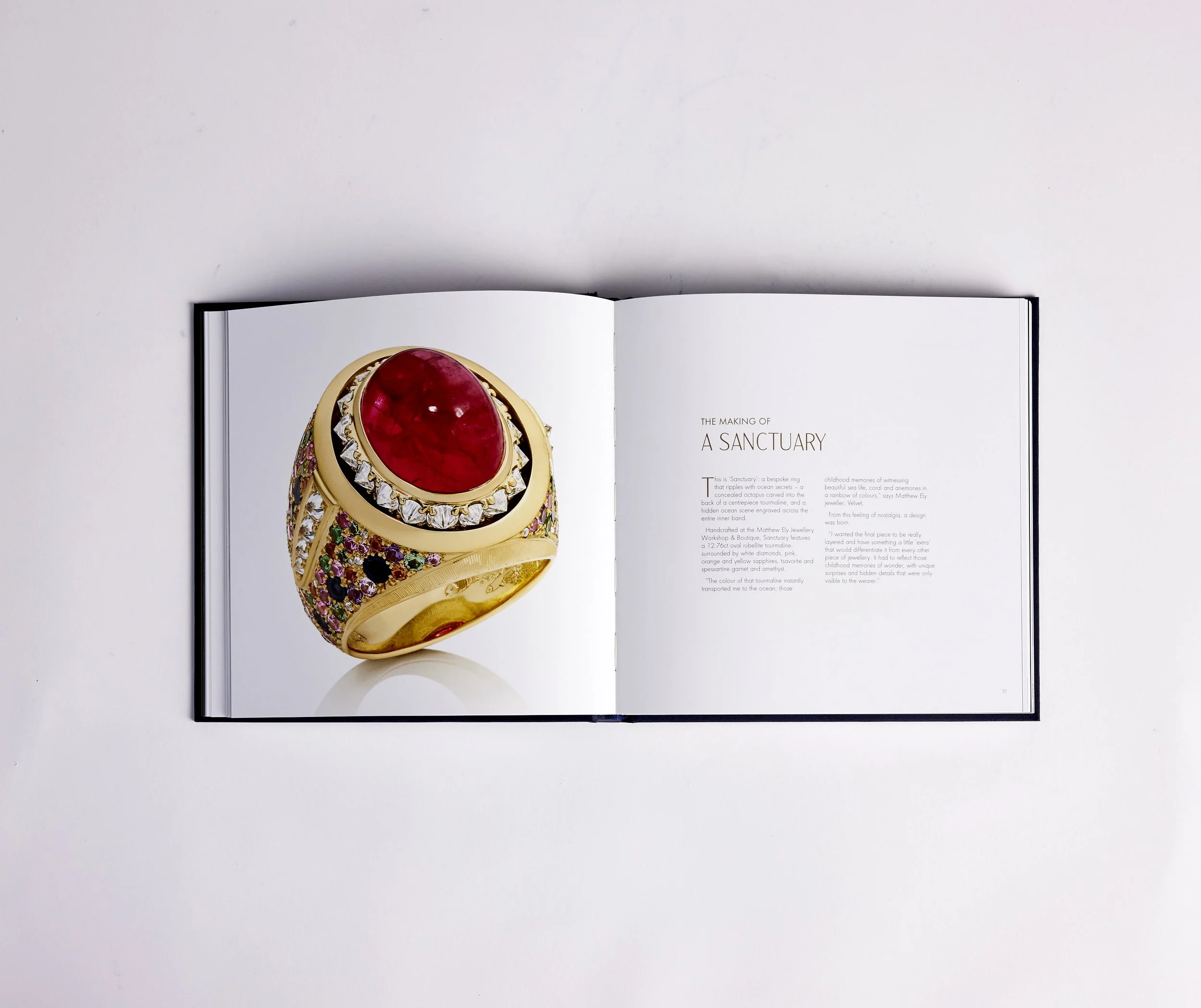 A pearl necklace with a large pearl pendant and intricate floral design, displayed in a blue jewelry box.