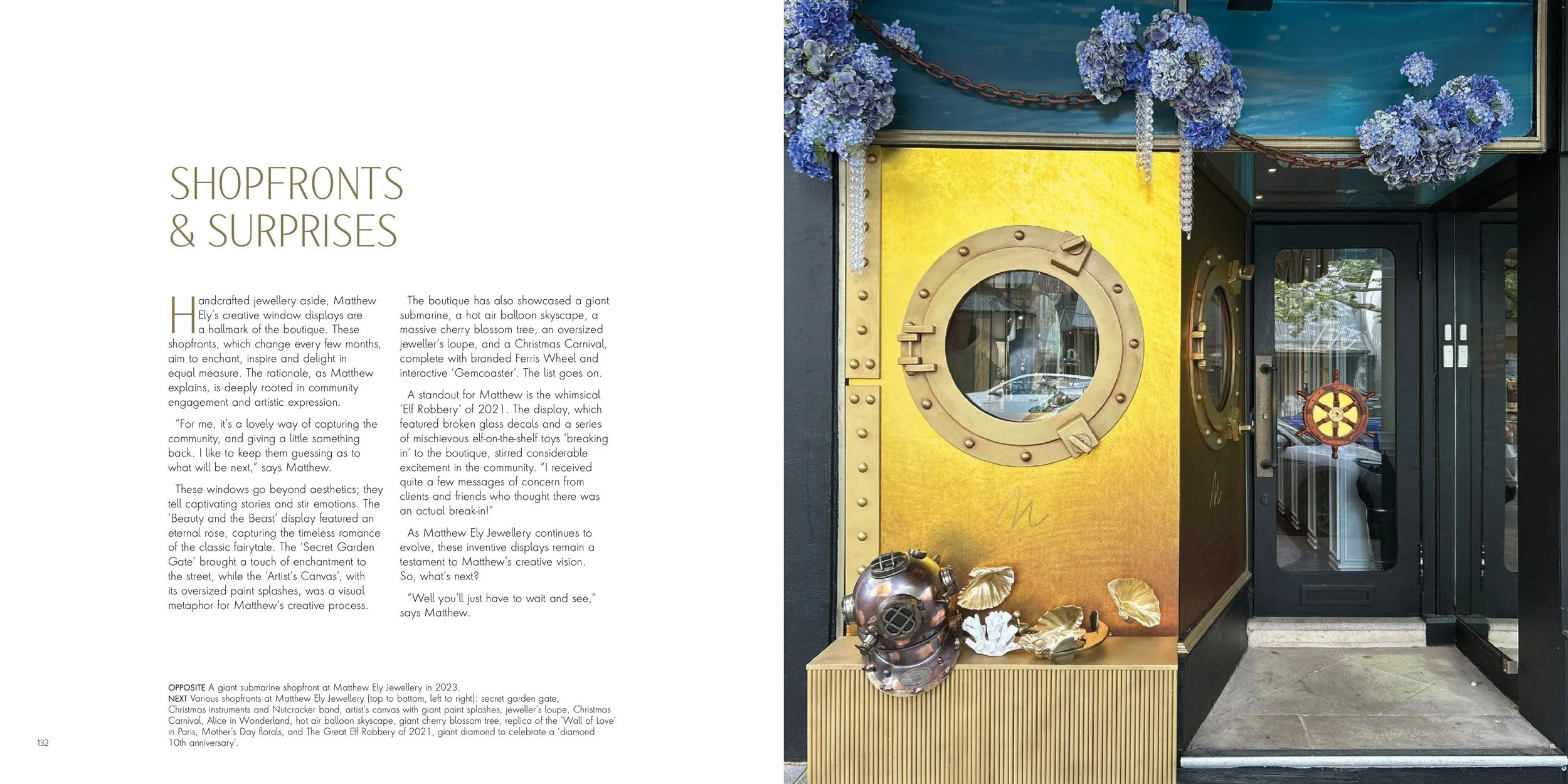 Storefront window decor with underwater theme featuring a vintage diving helmet and golden foliage, blue hydrangeas, and a yellow wall, with a glass door to the right.