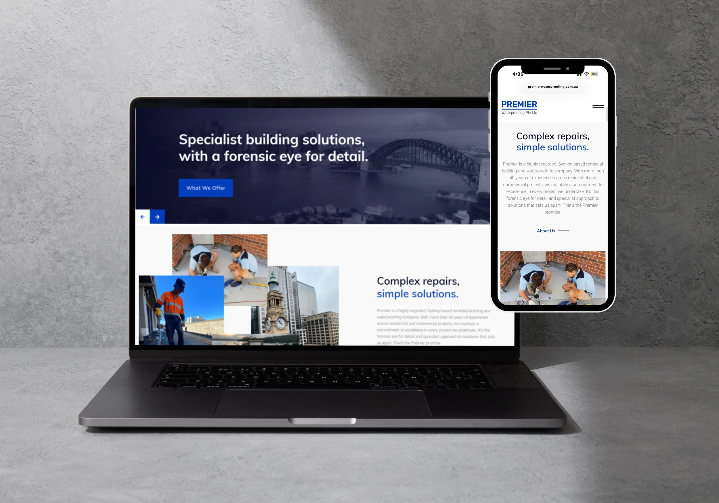 Laptop and smartphone displaying a construction or repair company's website with images of workers and cityscape in the background.