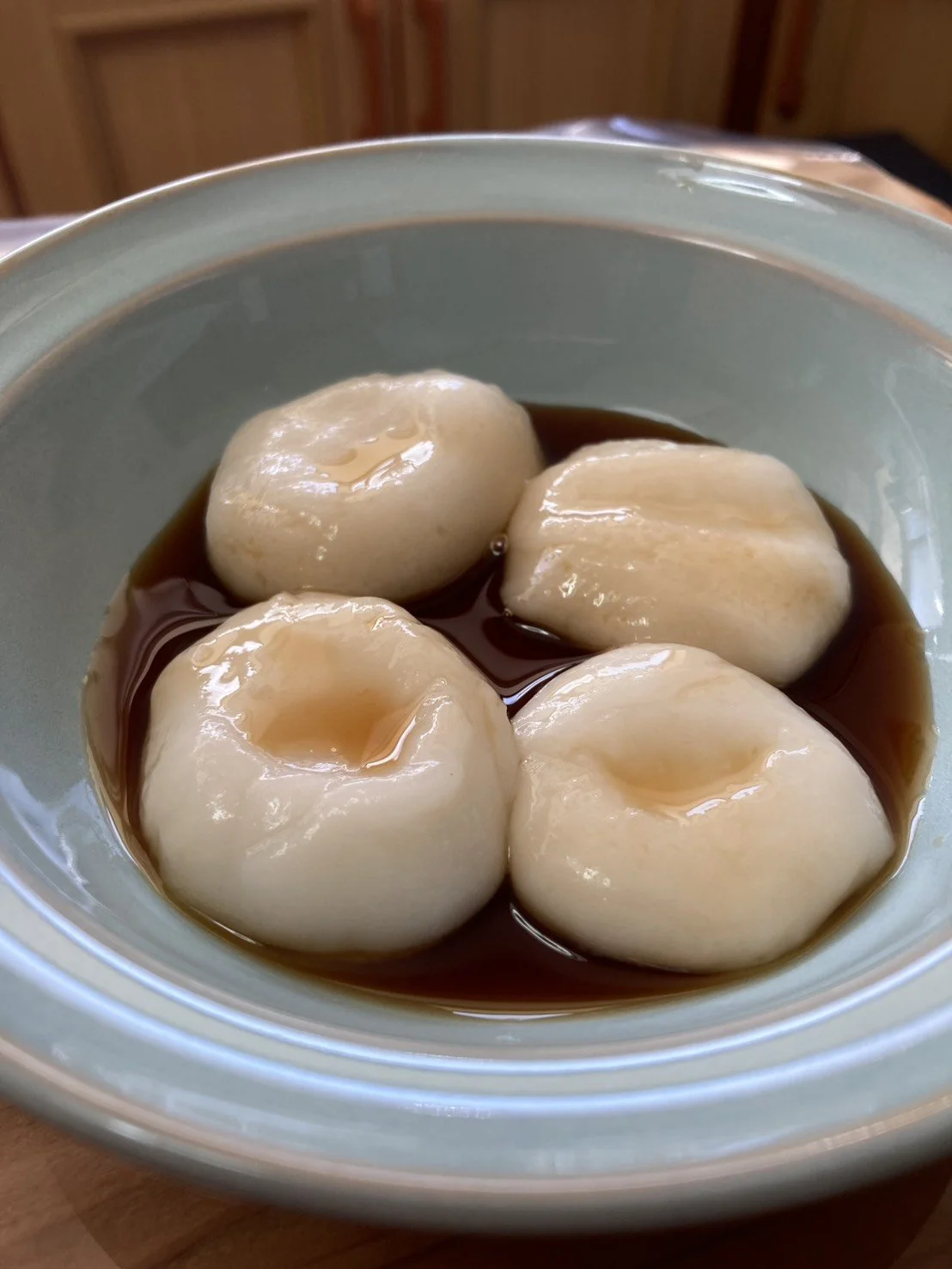 Boiled quail eggs in soy sauce in a light blue bowl.