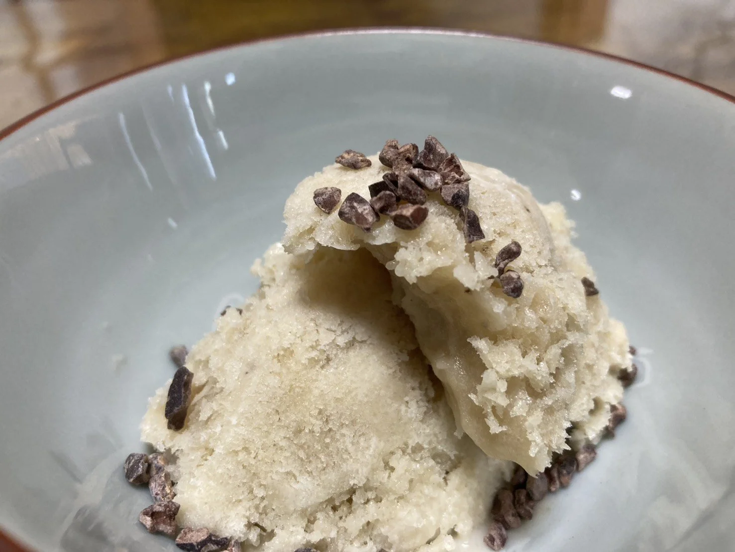 Vanilla ice cream scoops topped with chocolate sprinkles in a bowl.