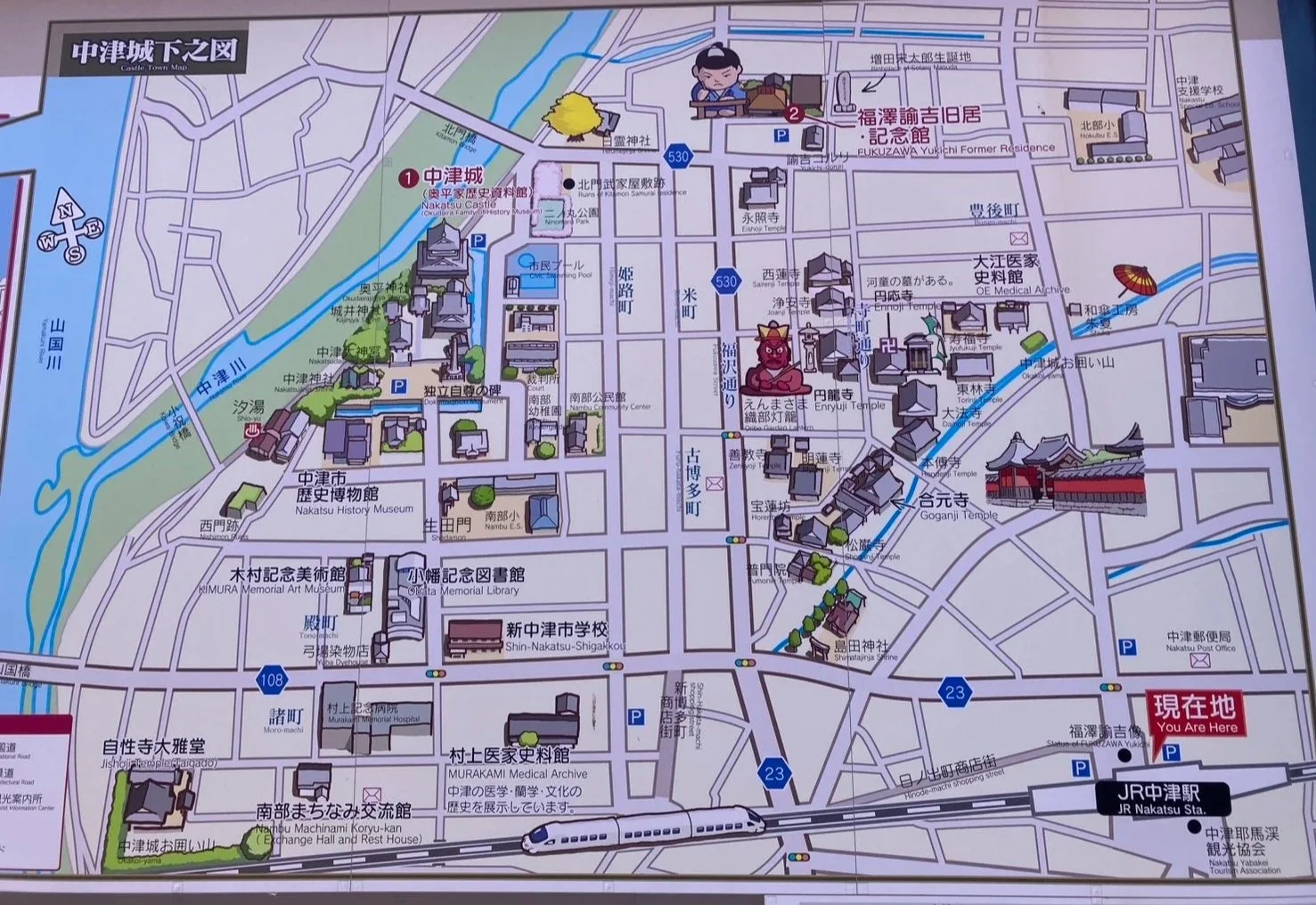 A detailed map of Nakatsu City featuring landmarks such as Nakatsu Castle, Nakatsu History Museum, KIMURA Memorial Art Museum, and JR Nakatsu Station, with roads, waterways, green spaces, and illustrations of buildings and landmarks.