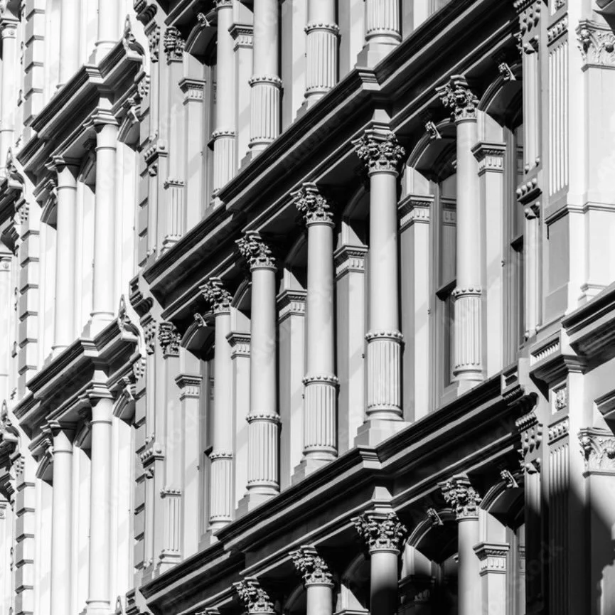 Black and white photo of a building facade with ornate architectural details, including columns and decorative molding.