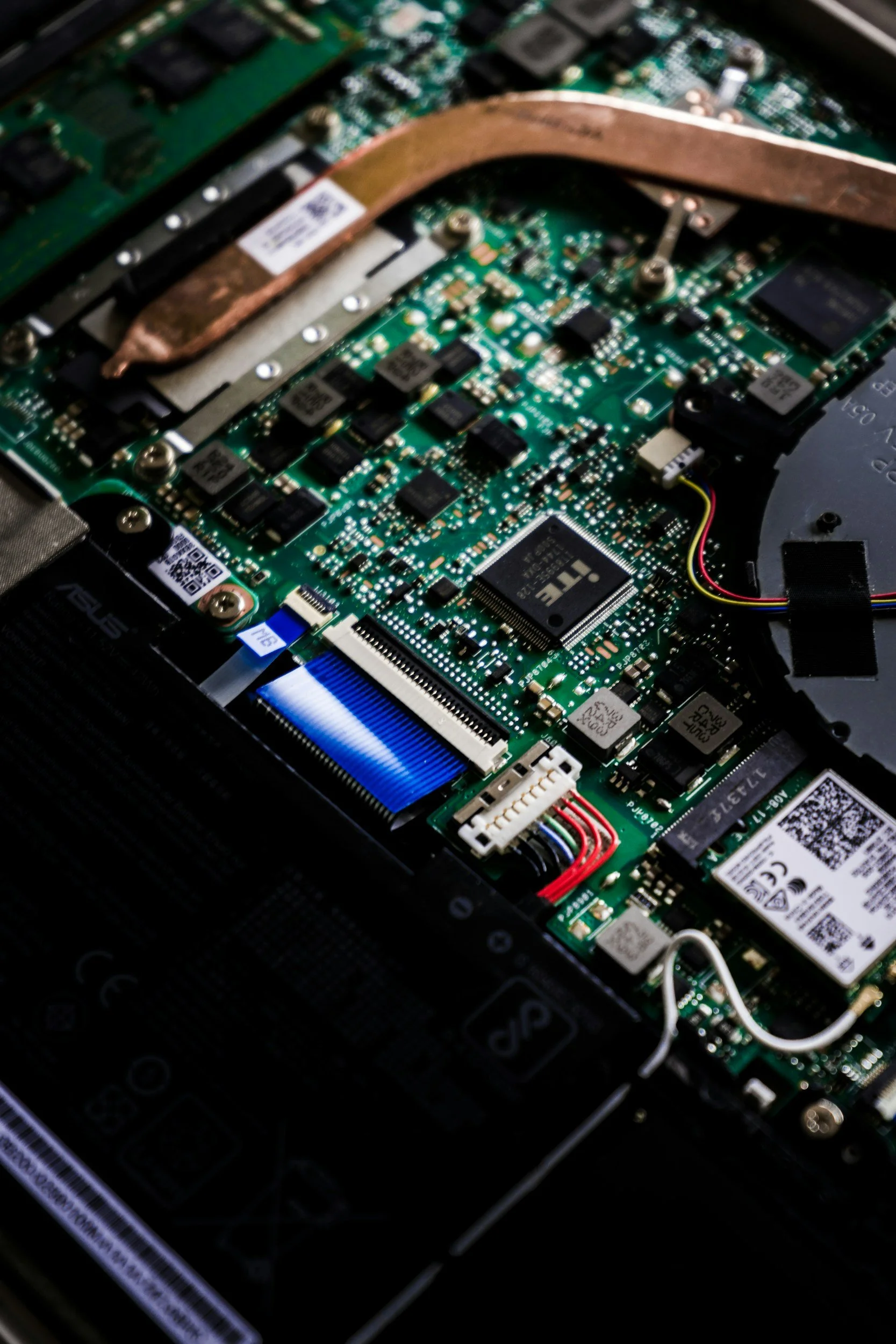Close-up view of a green printed circuit board inside a computer, with various electronic components, wires, and a copper heat pipe.