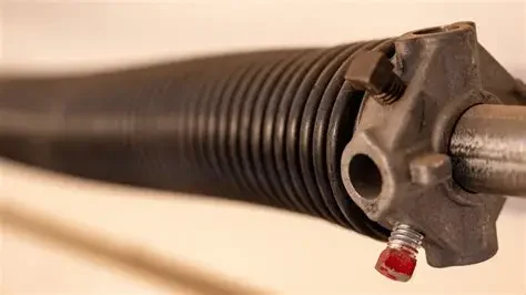 Close-up of a metal shock absorber with a black coil spring and red-tipped adjustment screw.