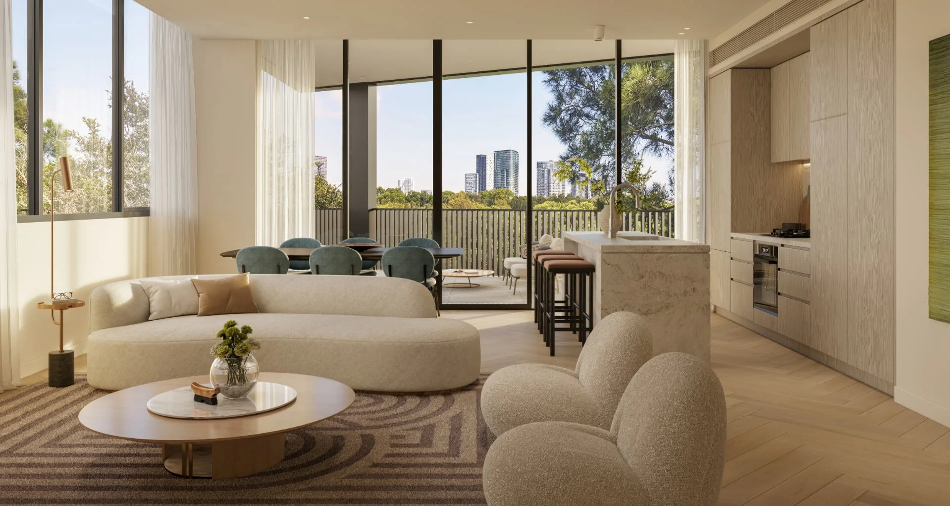 Modern living room with beige furniture, a round coffee table, and a view of a balcony with trees and city buildings in the background.