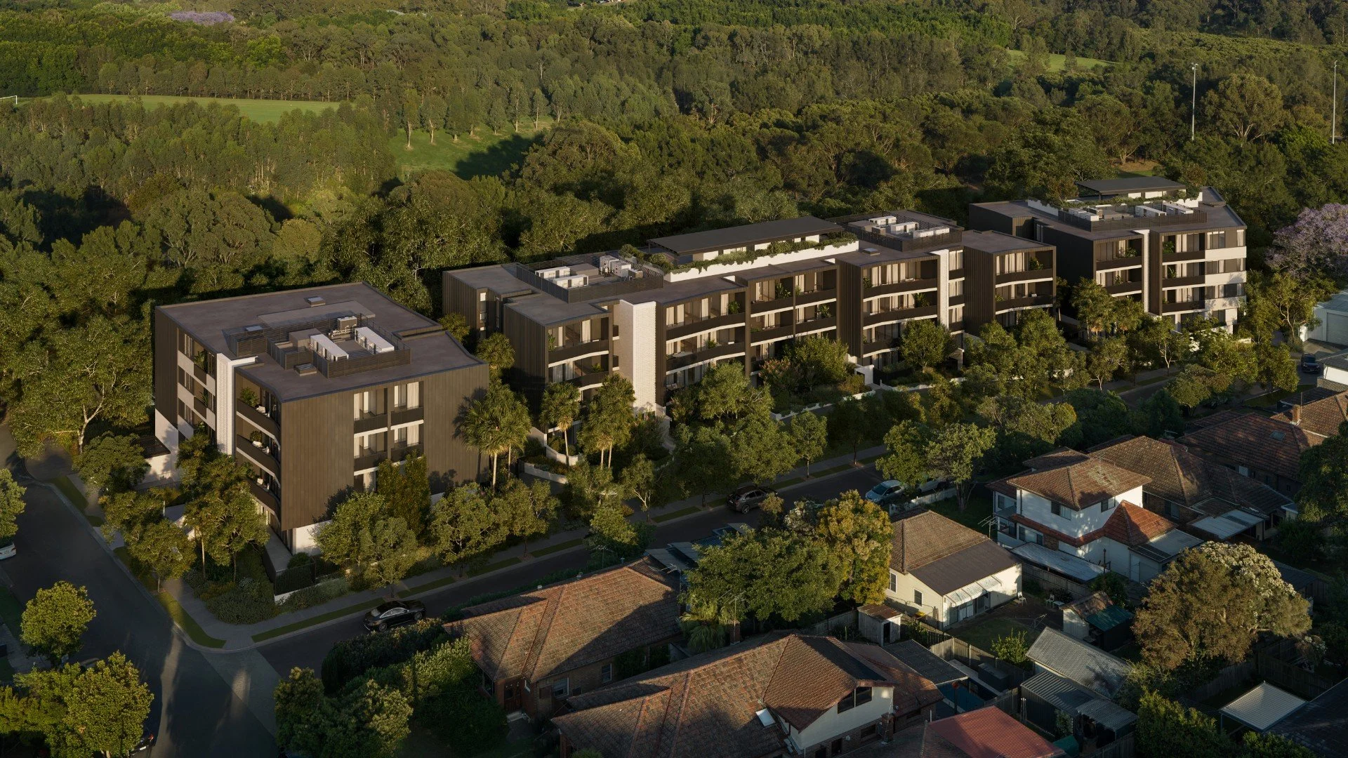 Aerial view of modern apartment buildings surrounded by trees and a residential neighborhood with houses.