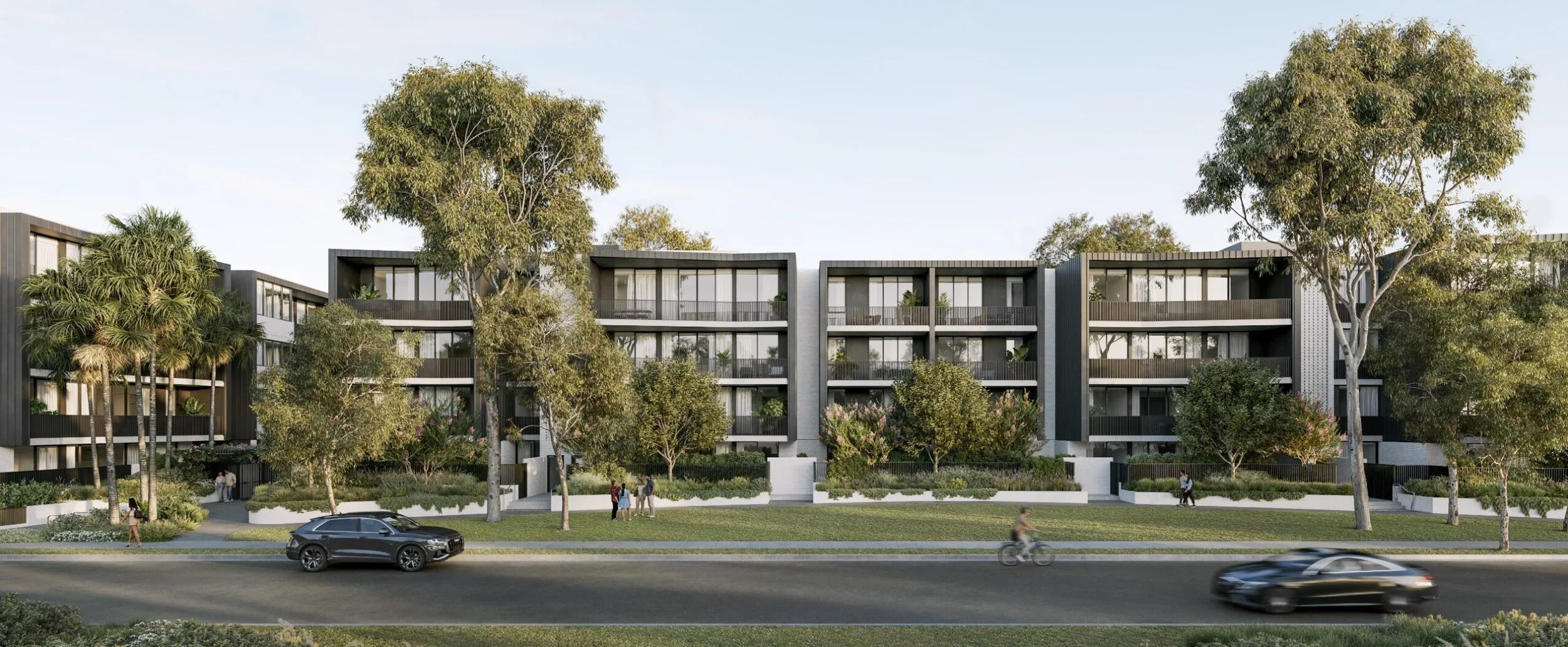 Modern multi-story apartment building with trees, grass, and people walking, cars on the street.