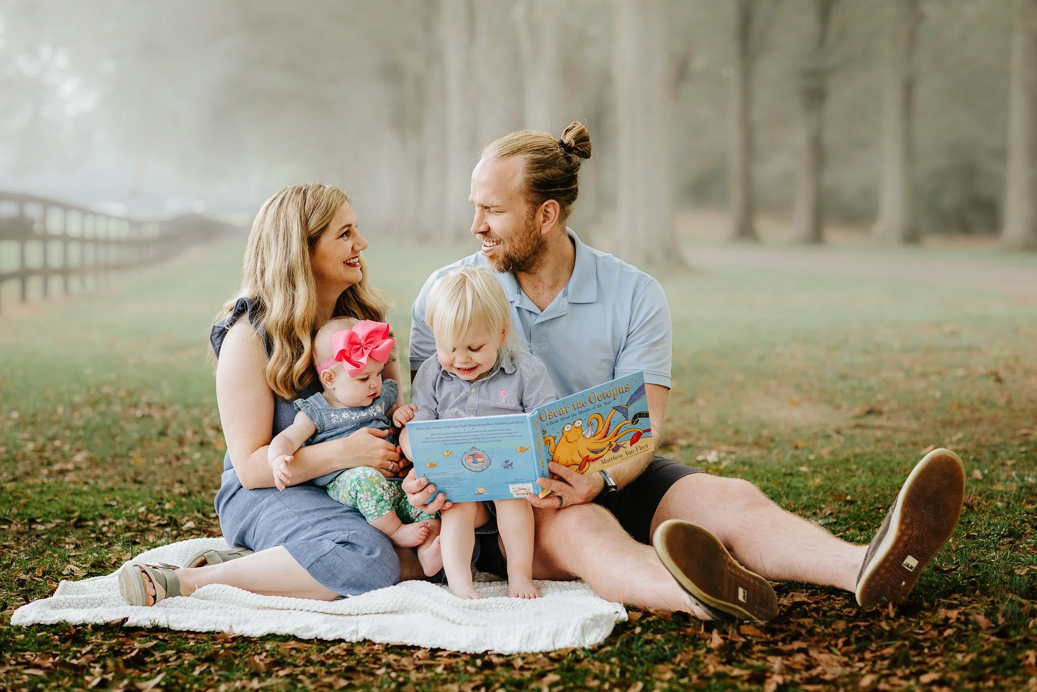 Family snuggle up and reading a book during outdoor session at Berry College in Rome, Georgia