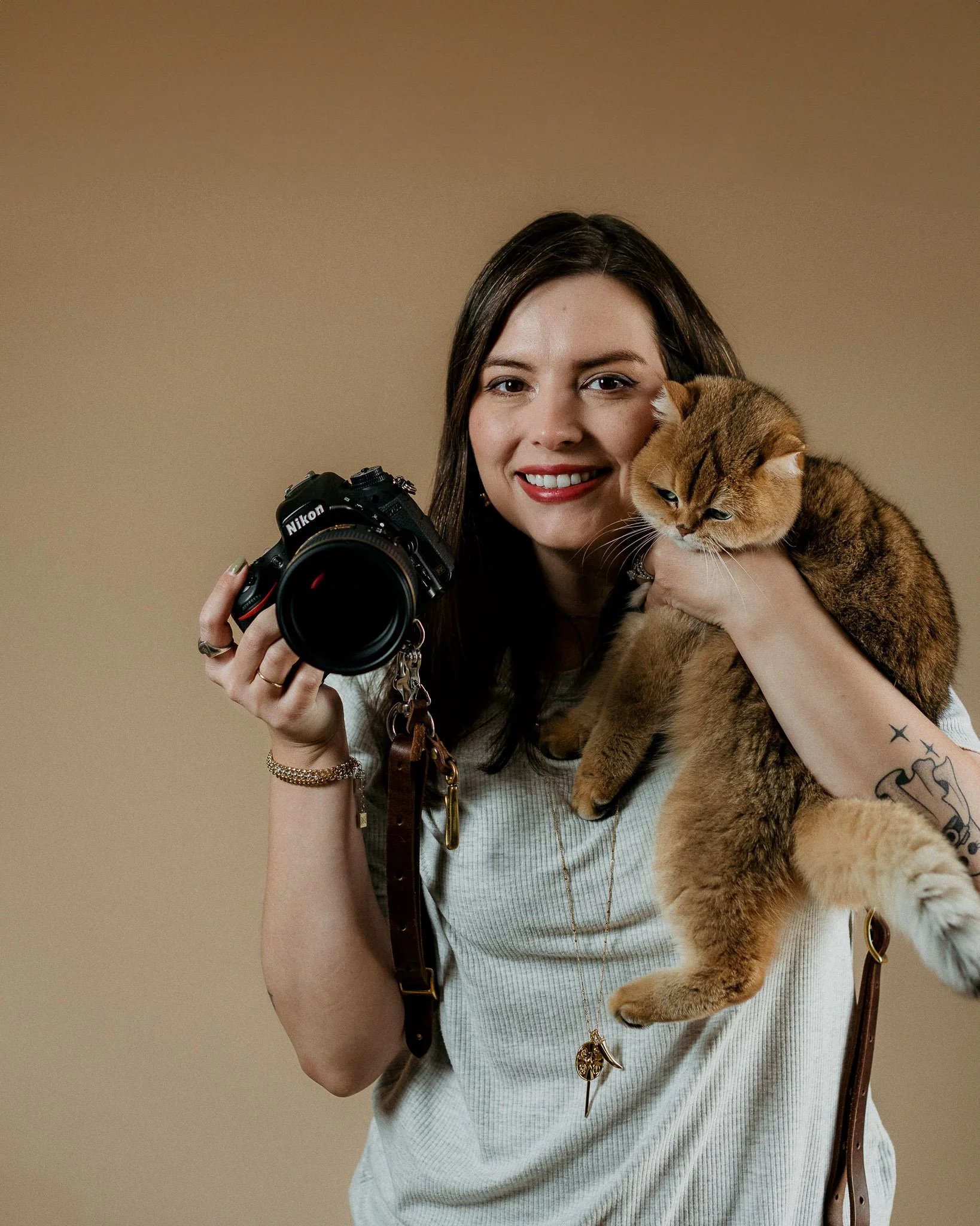 Branding portrait of photographer holding camera and cat in studio by Raquel Zane Photography