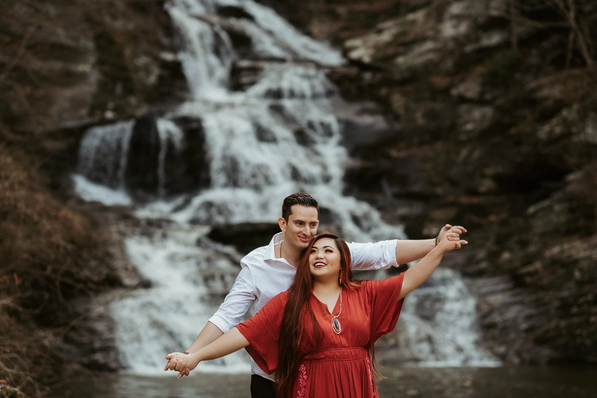 Couple holding hands in front of waterfall in North Georgia by Raquel Zane Photography