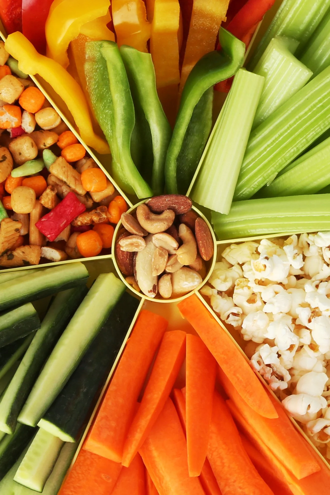 Close up of sliced vegetables and snacks in a yellow container.