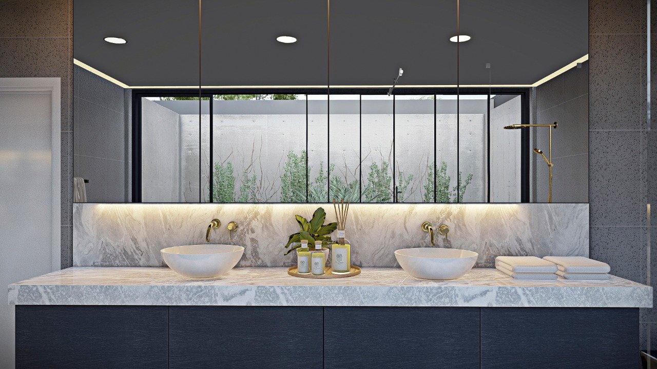 Modern bathroom vanity with double vessel sinks, gold fixtures, and a large mirror reflecting a window with a view of greenery outside.