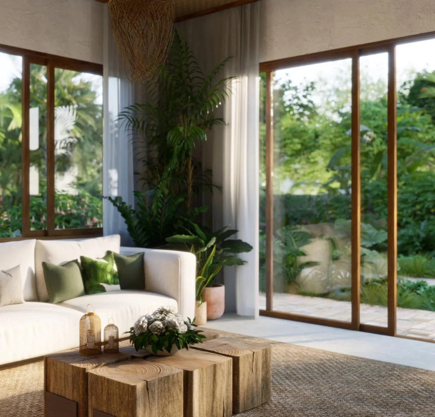 Bright living room with large windows revealing a lush green outdoor garden. A white sofa with green throw pillows sits in front of a wooden coffee table decorated with lanterns and a flower arrangement. Tall potted plants and white curtains enhance the airy, natural atmosphere.