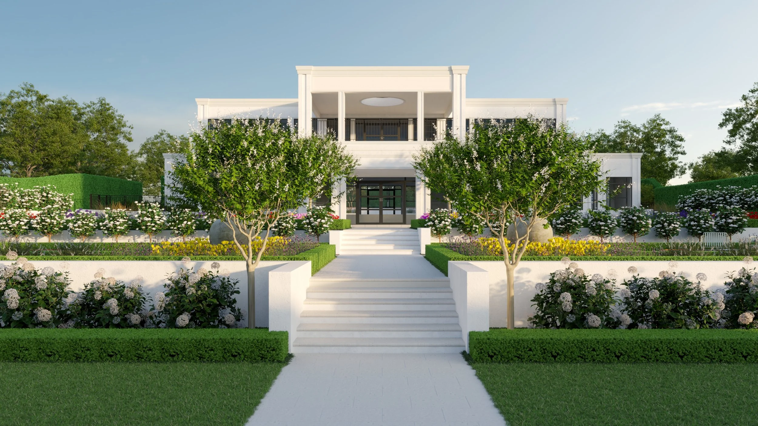 A modern white house with multiple levels, surrounded by lush greenery, flowering bushes, and trees, with a white walkway leading to the entrance.