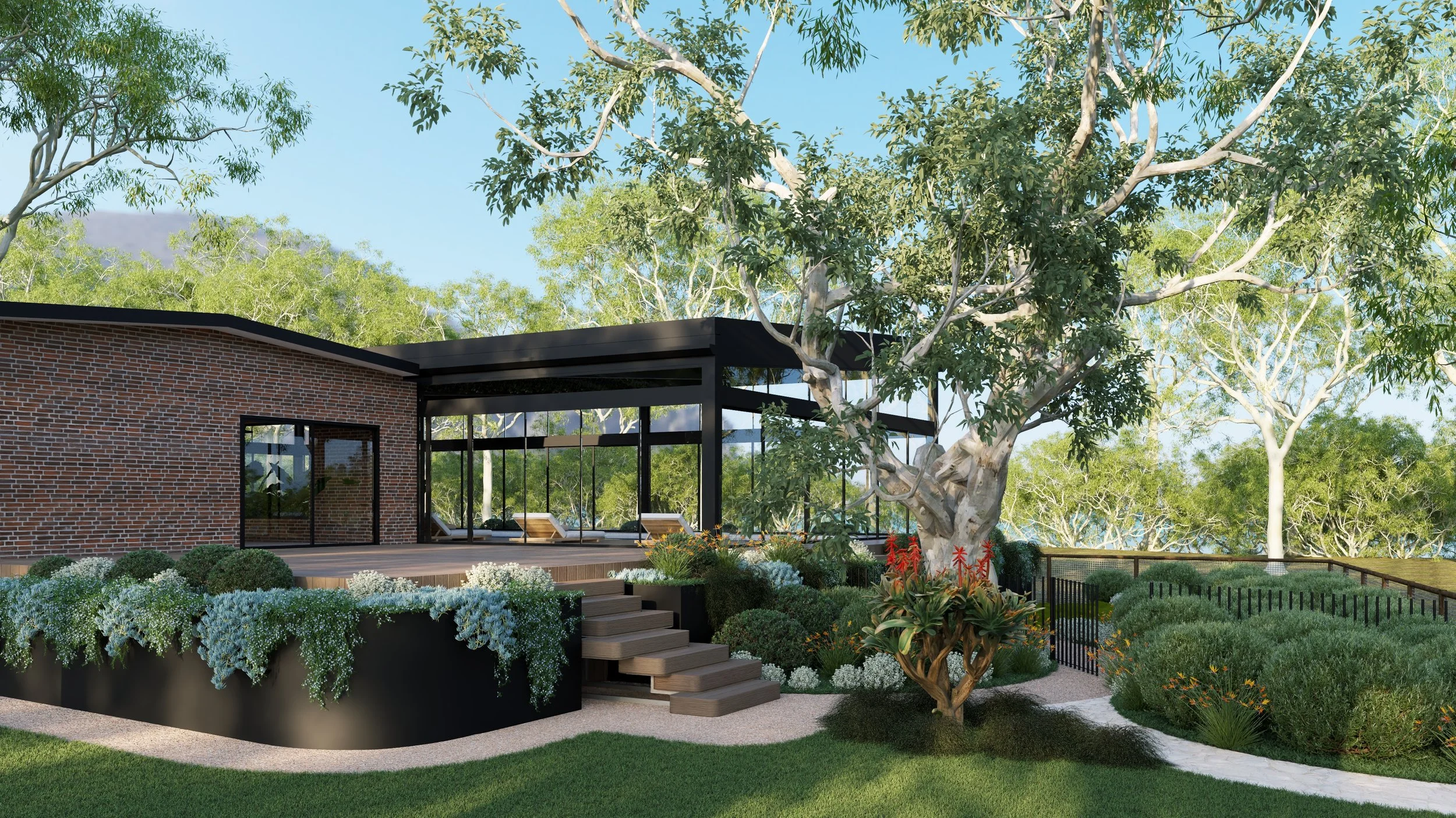 Modern backyard with a brick house, large trees, a shaded patio area, wooden steps, lush green grass, and landscaped shrubs and flowering plants.